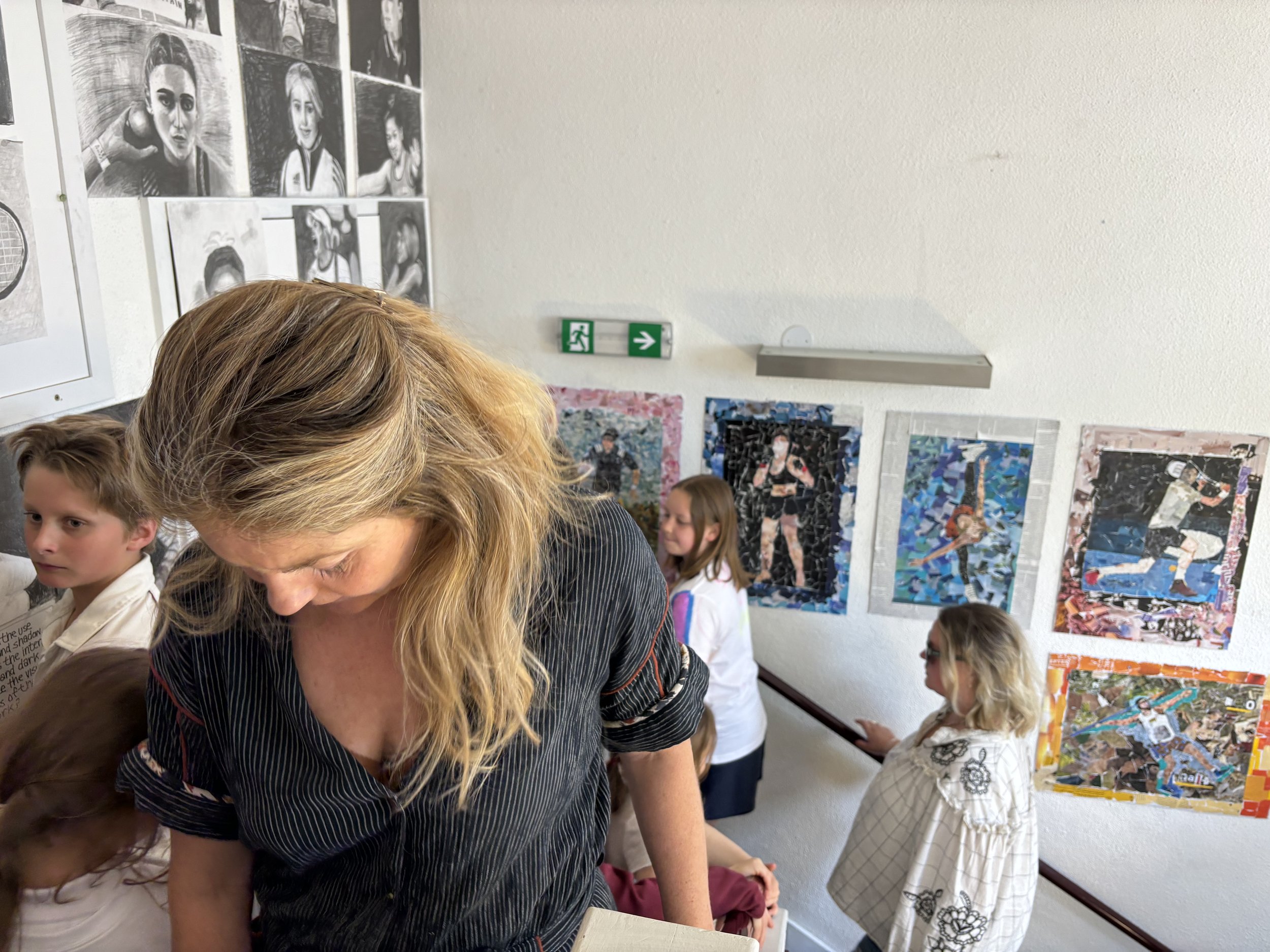 A woman and children in an art gallery, with colorful portraits and artwork displayed on the walls.