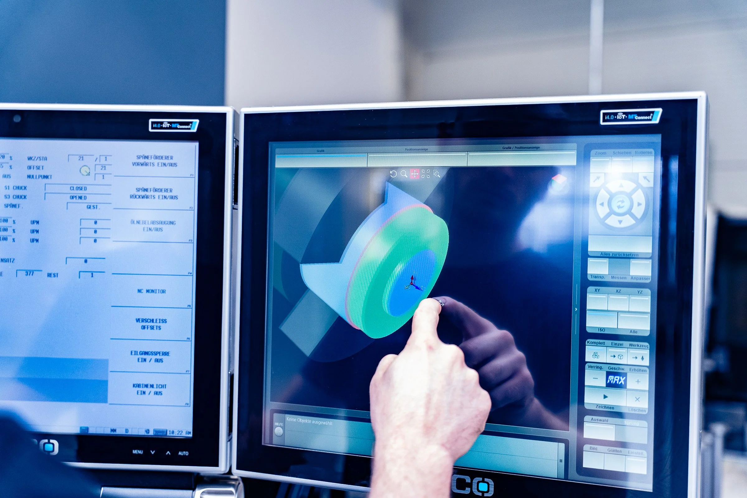 Person bedient einen Computerbildschirm mit einer 3D-Visualisierung eines technischen Objekts in einer Fabrikumgebung.