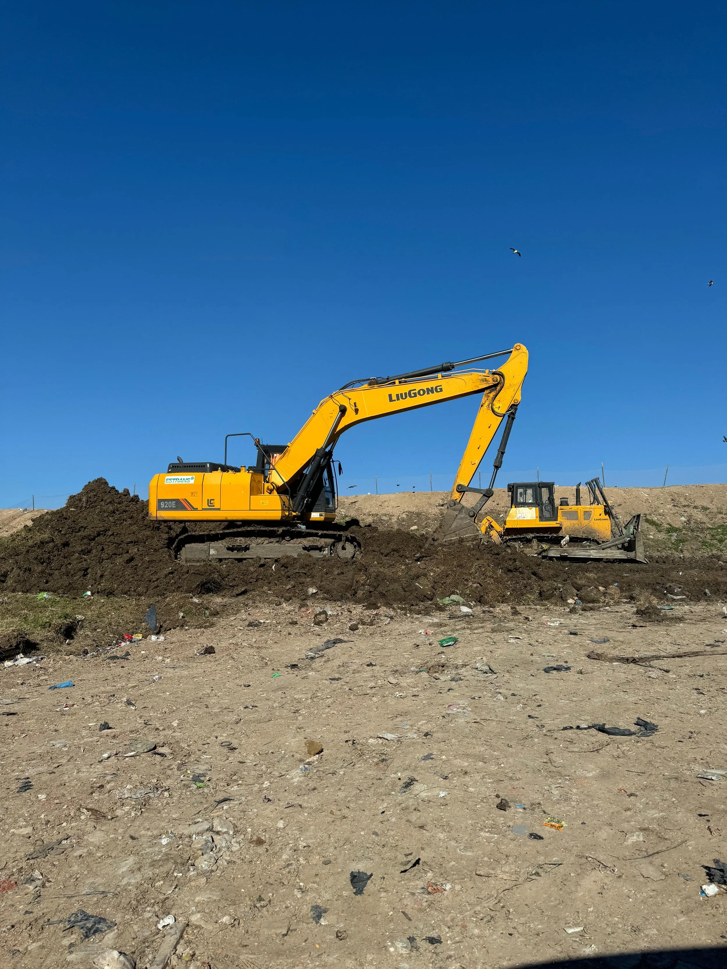 Excavadora amarilla trabajando en un terreno con cielo azul al fondo
