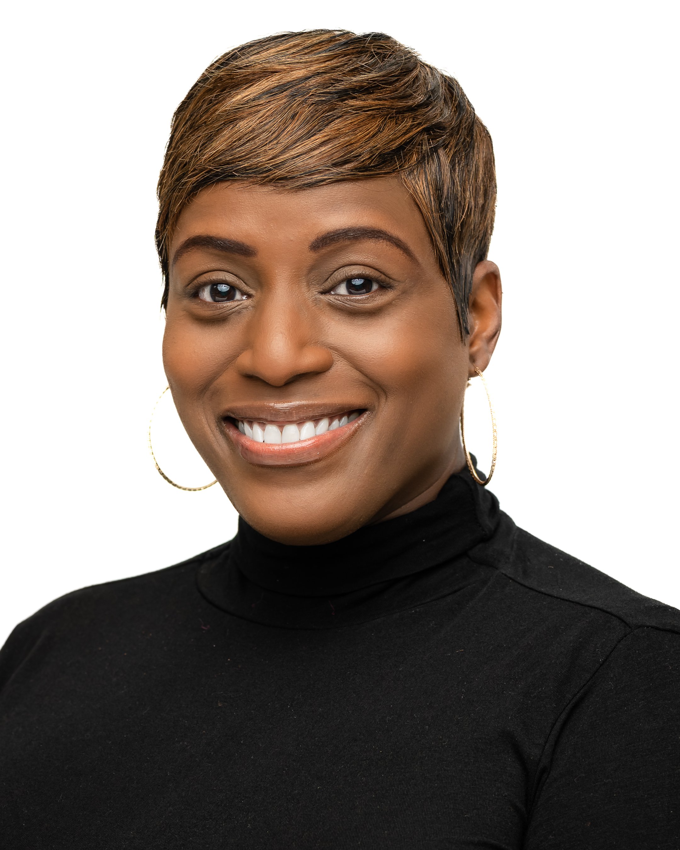 A woman with short, styled hair smiling, wearing hoop earrings and a black turtleneck shirt.