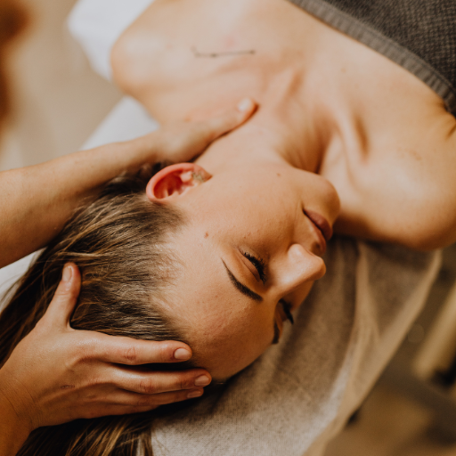 Close-up of a woman receiving a massage, lying on her stomach with her eyes closed, smiling peacefully.