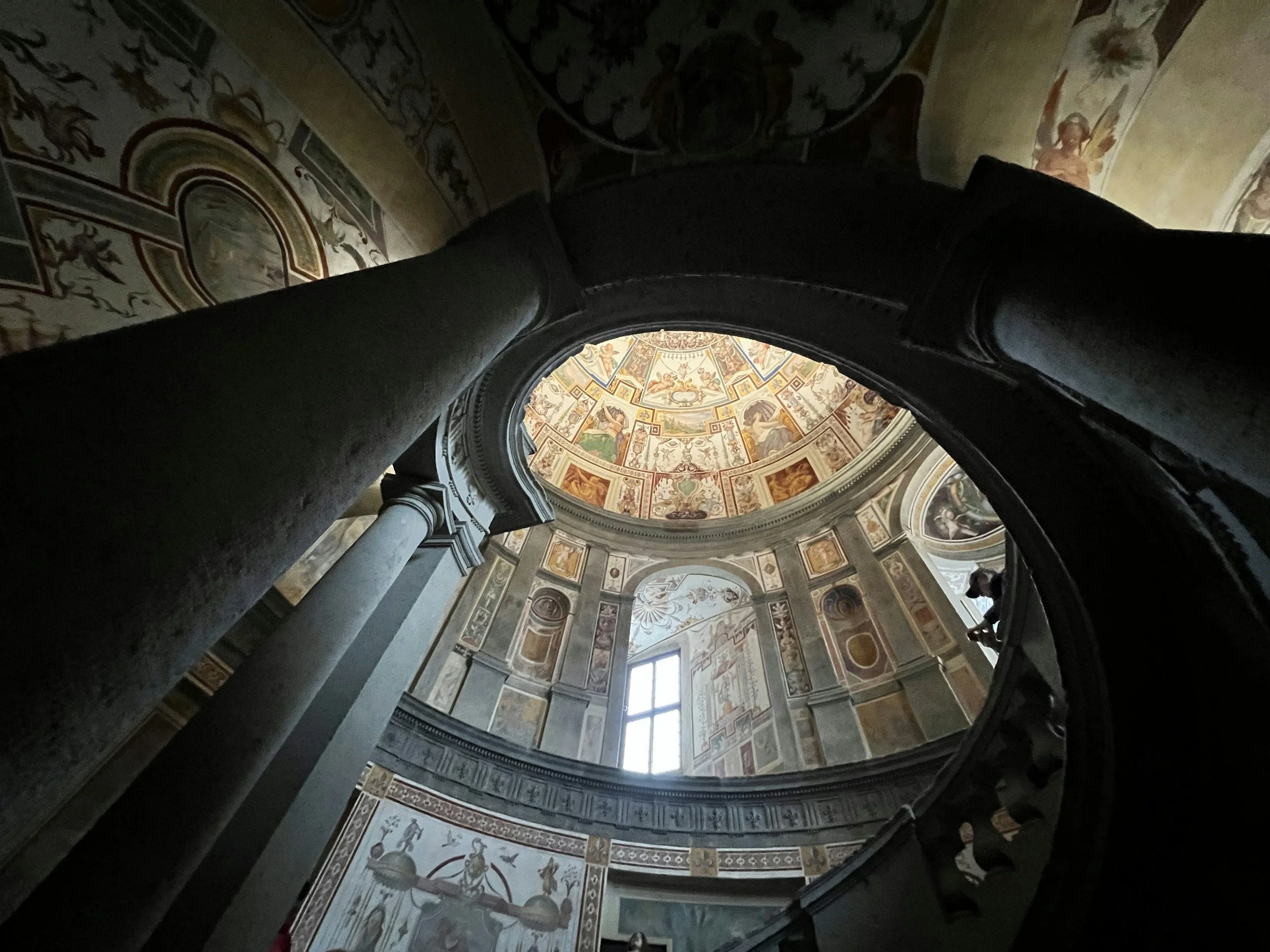 Interno di una chiesa con affreschi sul soffitto rotondo, colonne di marmo e una finestra centrale che lascia entrare luce.