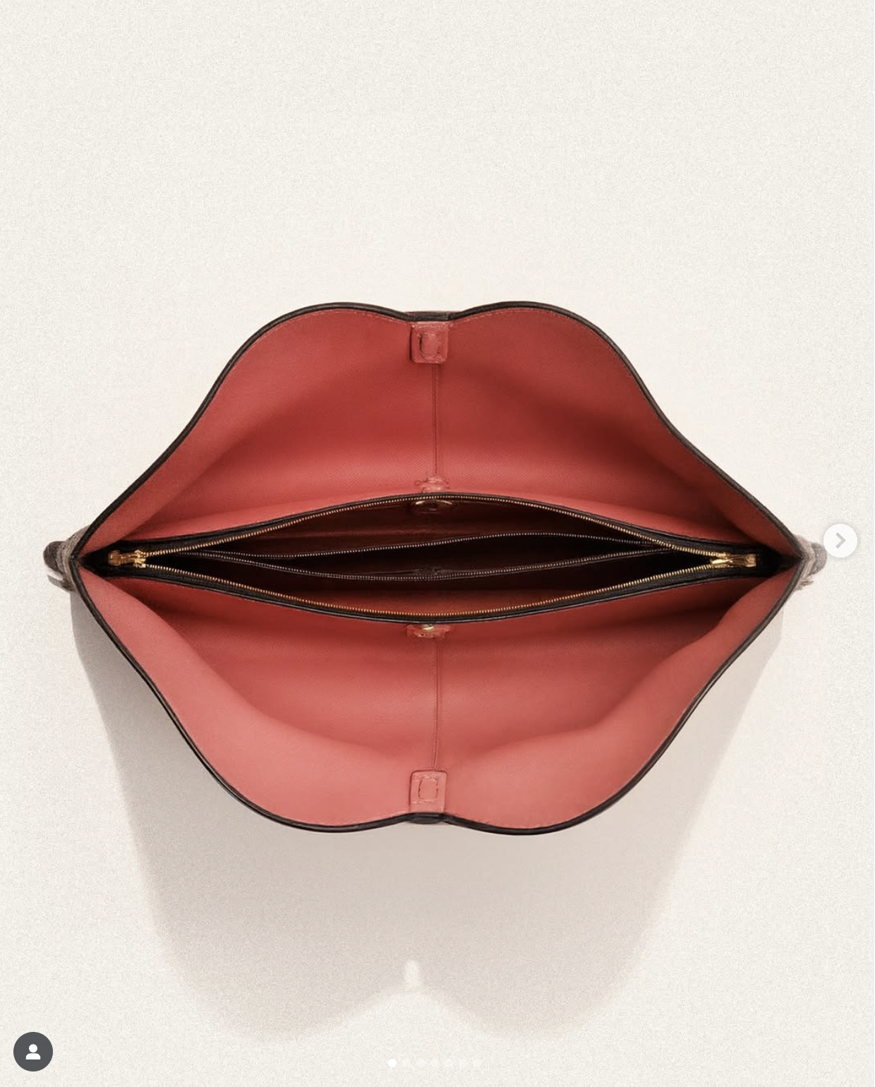 Open tote bag with pink interior and black exterior, showing several zipped compartments inside.