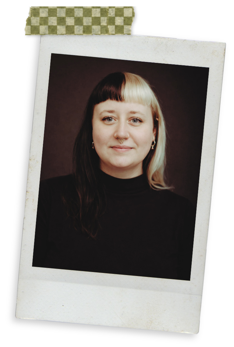 Ein Porträtfoto einer Frau mit Piercings, schwarzem T-Shirt und zweifarbiger Frisur auf einem alten, randbemalten Fotokarton, der mit grün gemustertem Tape befestigt ist.