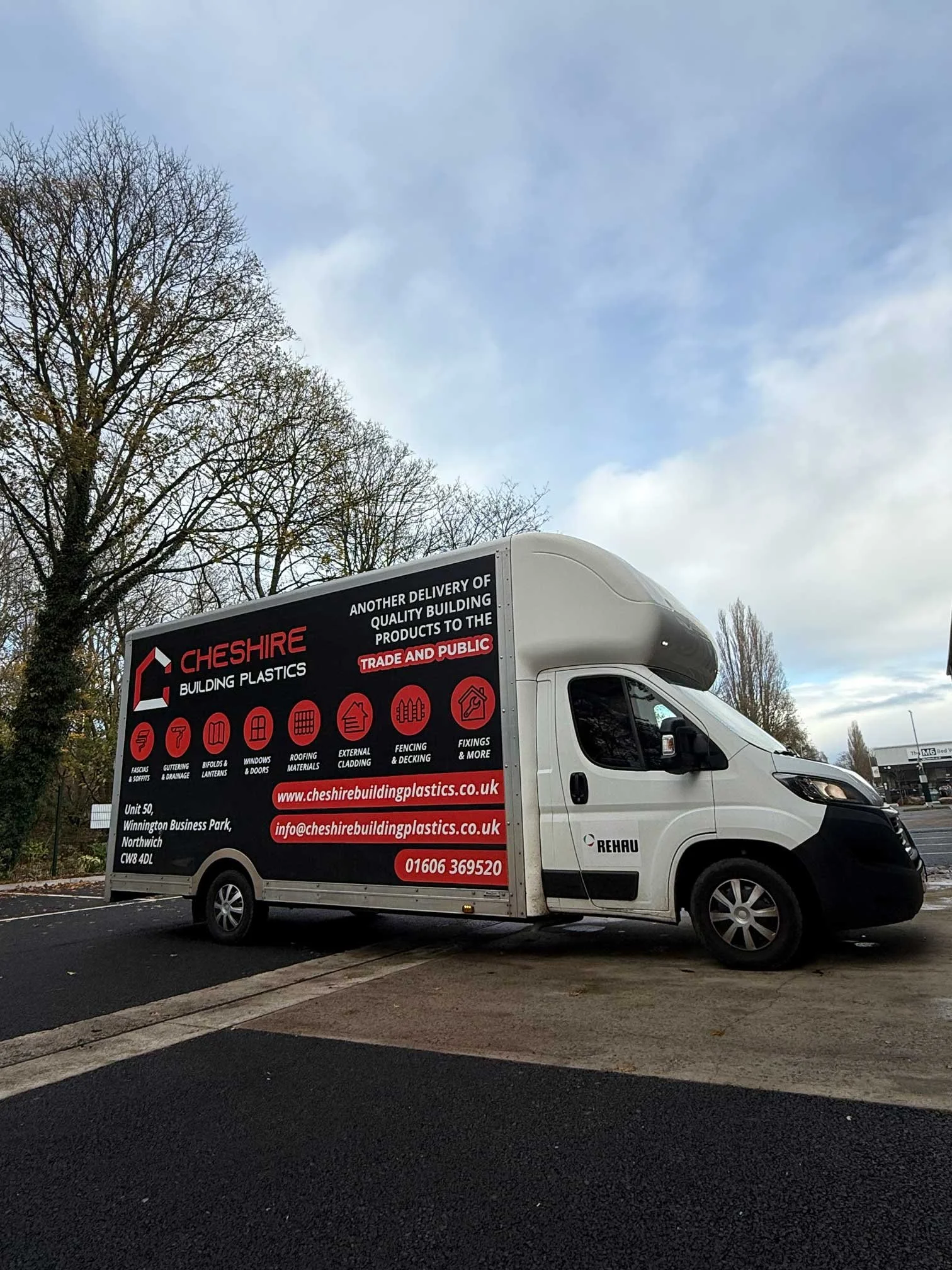A delivery van parked outdoors, advertising Cheshire Building Plastics for construction materials with contact details.