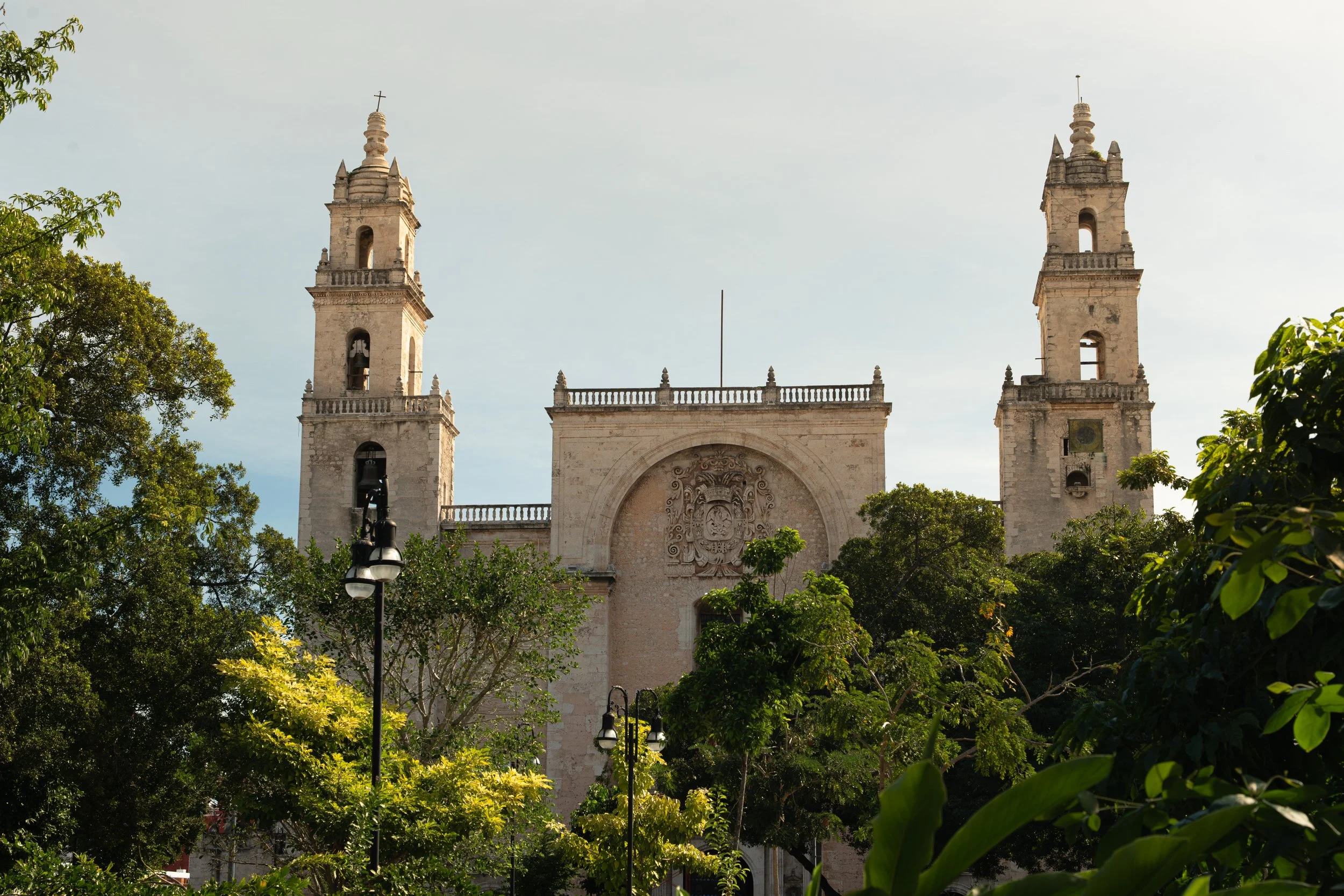 A historic church with two bell towers, surrounded by green trees and a clear sky.