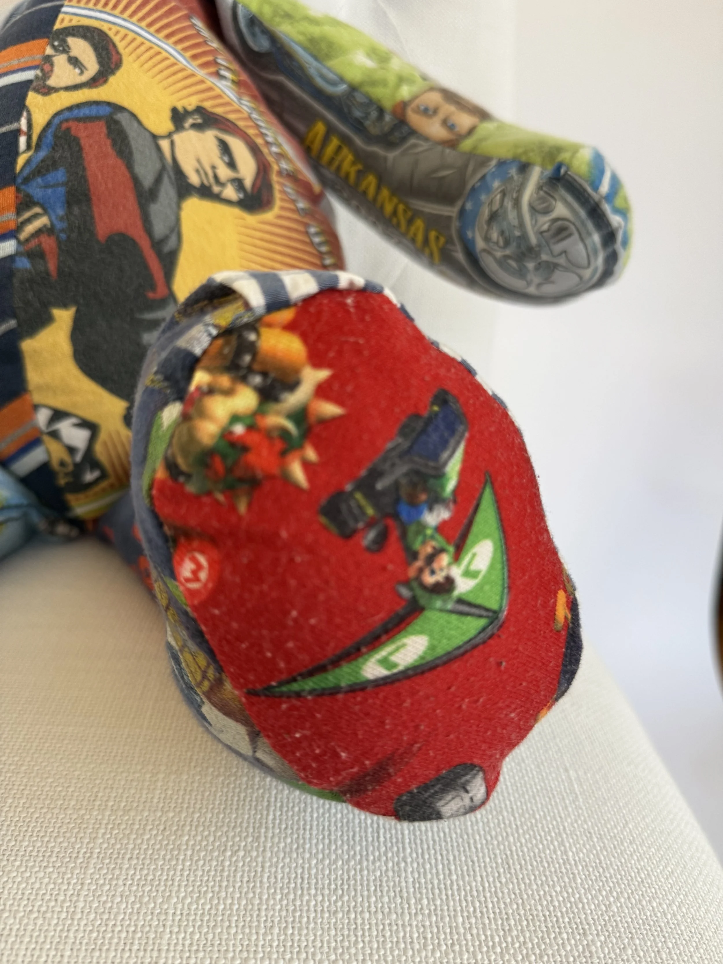 Close-up of a group of colorful children's fabric books with characters from superhero and animated franchises.