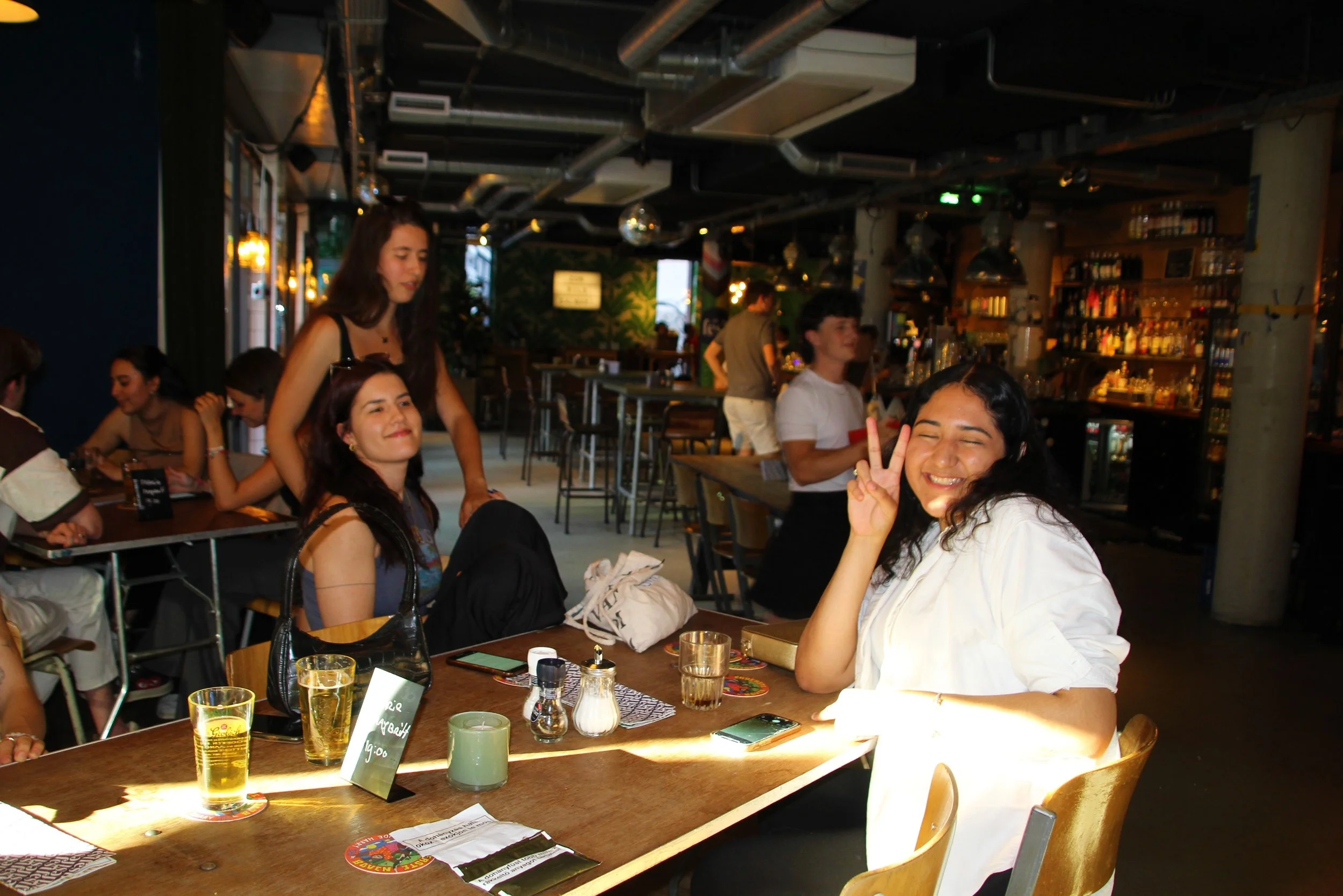 A group of young Eastern European women enjoying their time at a restaurant, with one woman in the foreground smiling and making a peace sign.