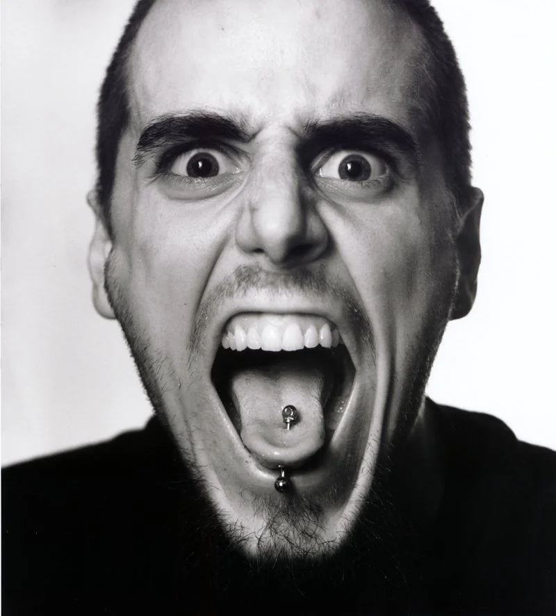 A man with wide eyes and an open mouth showing teeth and a tongue piercing. Created by Sam Devine Tischler © all rights reserved