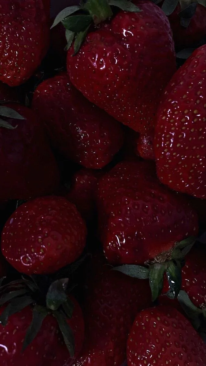 Close-up of ripe red strawberries with green leaves.