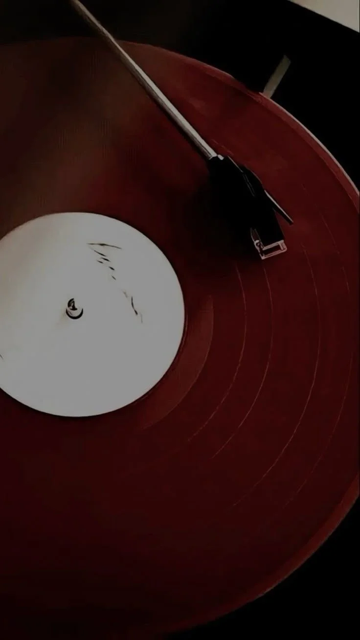 A close-up image of a vintage vinyl record on a turntable, with the tonearm resting on it.