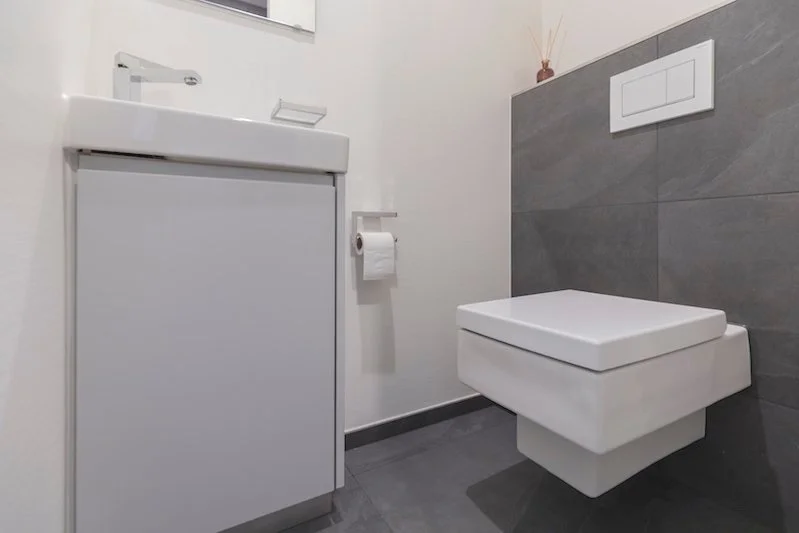 Modernes Badezimmer mit weißen Toilette, rotem Zierde und Spiegelschrank.