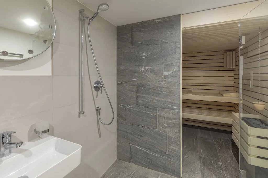 Badezimmer mit Dusche und angrenzender Sauna