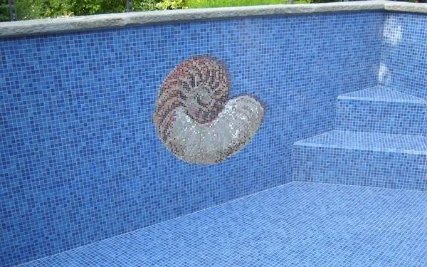 Innenbereich eines Pool mit azurblauer Mosaikwand und einer Muschel-Mosaikdekoration
