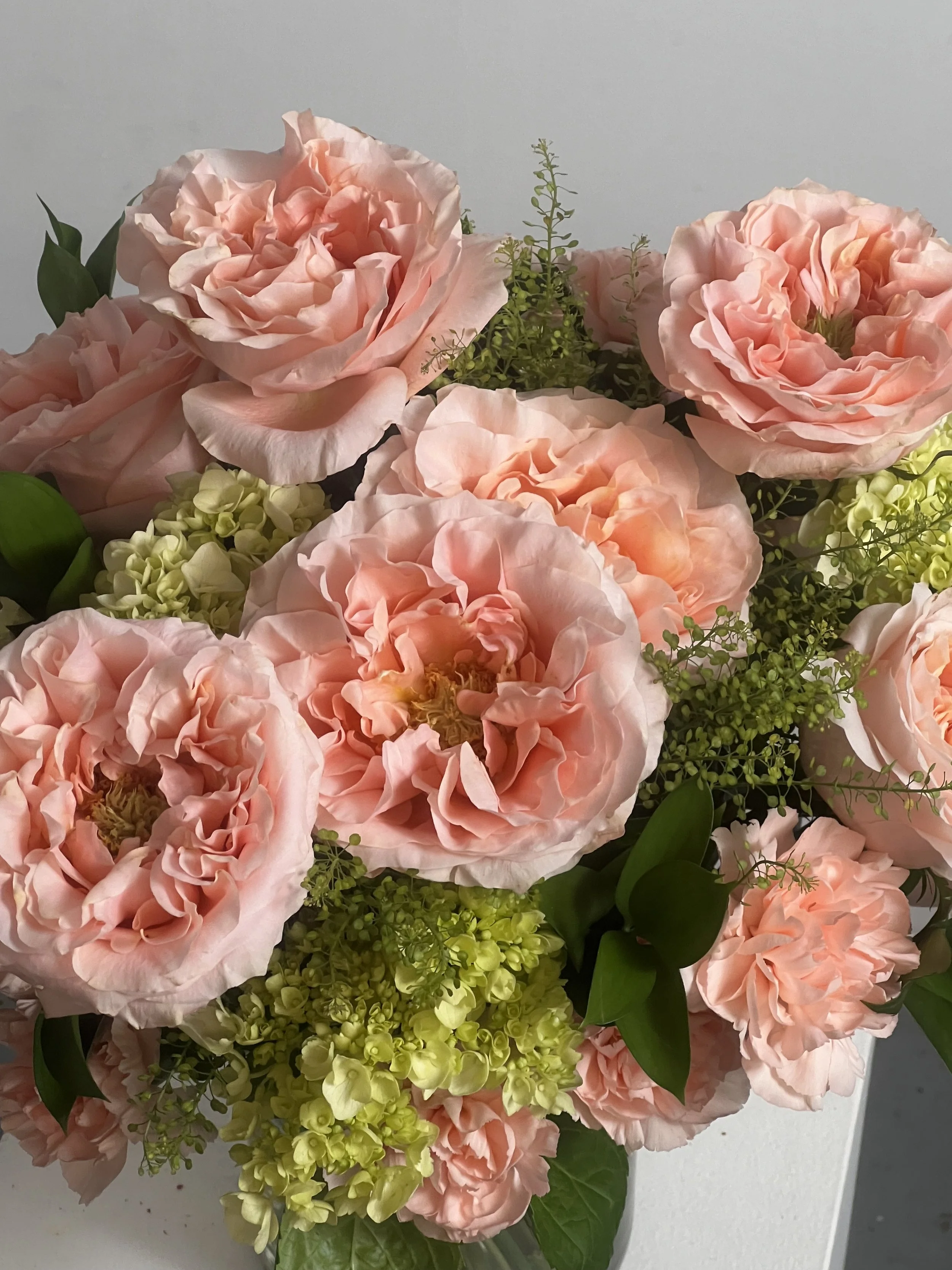 Un bouquet de roses roses pâles, de hortensias vert clair et de verdure