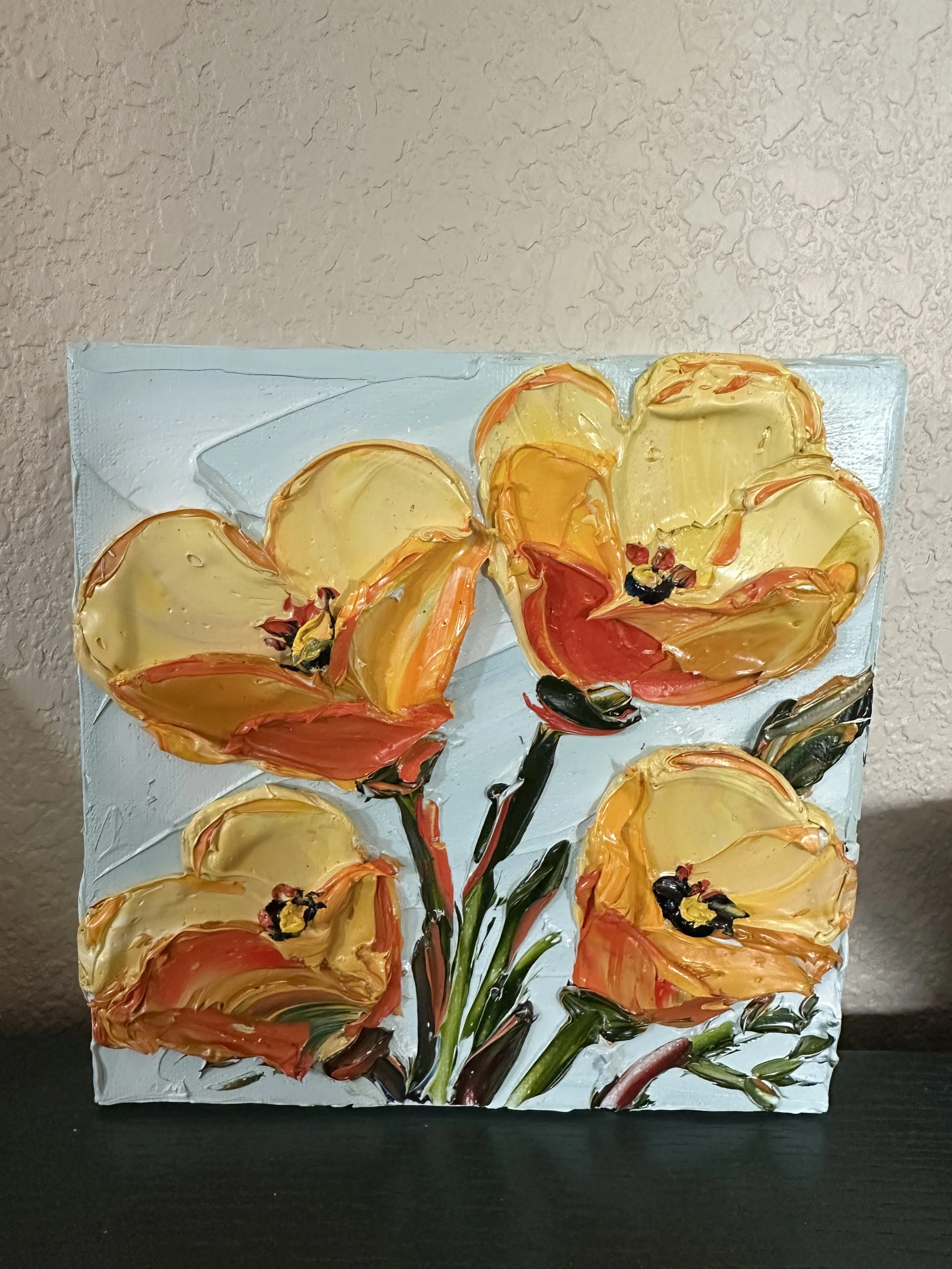 A painting of a bunch of yellow and orange flowers with dark stems and leaves on a white textured canvas.