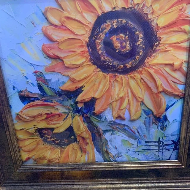 Oil painting of bright yellow sunflowers with thick, textured brushstrokes in a wooden frame.