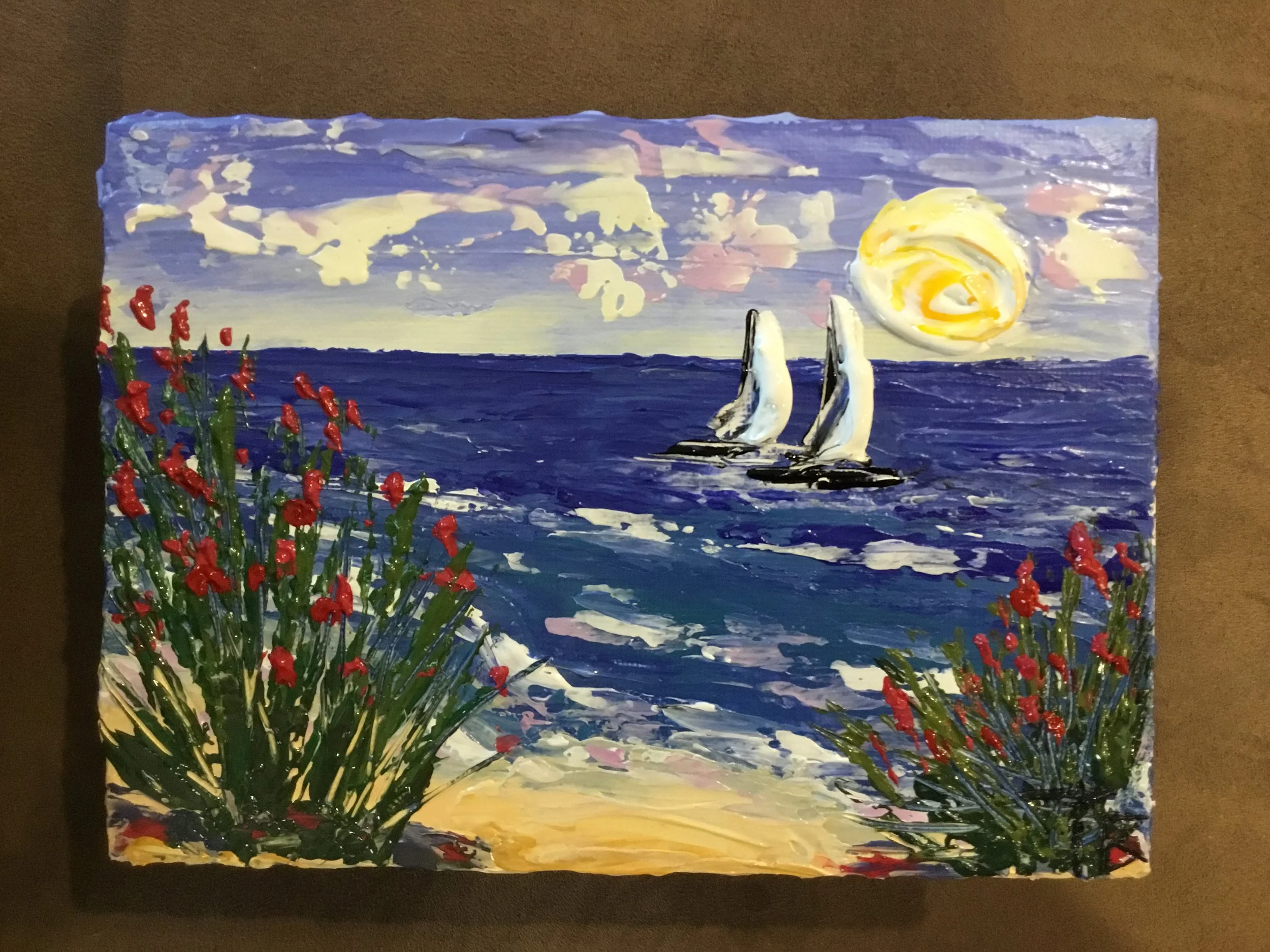 A vibrant painting of a seascape at sunset with red flowers in the foreground, a sailboat on the water, a colorful sky with clouds, and a large yellow and white sun.