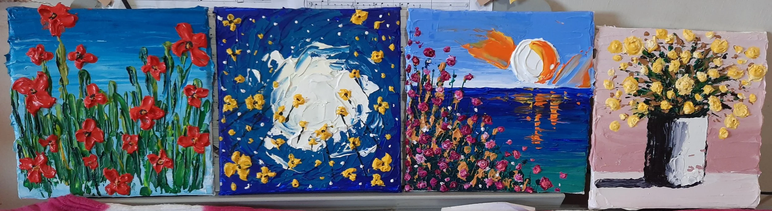 Five painted canvases depicting various floral and nature scenes, arranged side by side. The first shows red flowers with green stems against a blue sky background. The second features a moonlit night scene with a large white moon and yellow flowers 