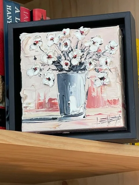 Impressionist-style painting of a white vase with white flowers, placed on a surface with a pink and white background.