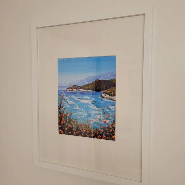 Painting of a coastal landscape with a river, rocky cliffs, and a hillside with flowers under a blue sky.