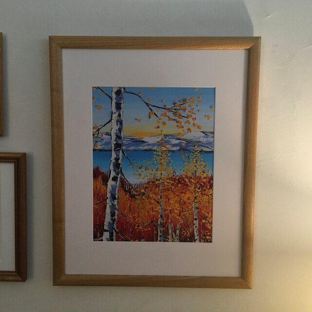 Painting of autumn birch trees near a lake with snow-capped mountains in the background at sunset.