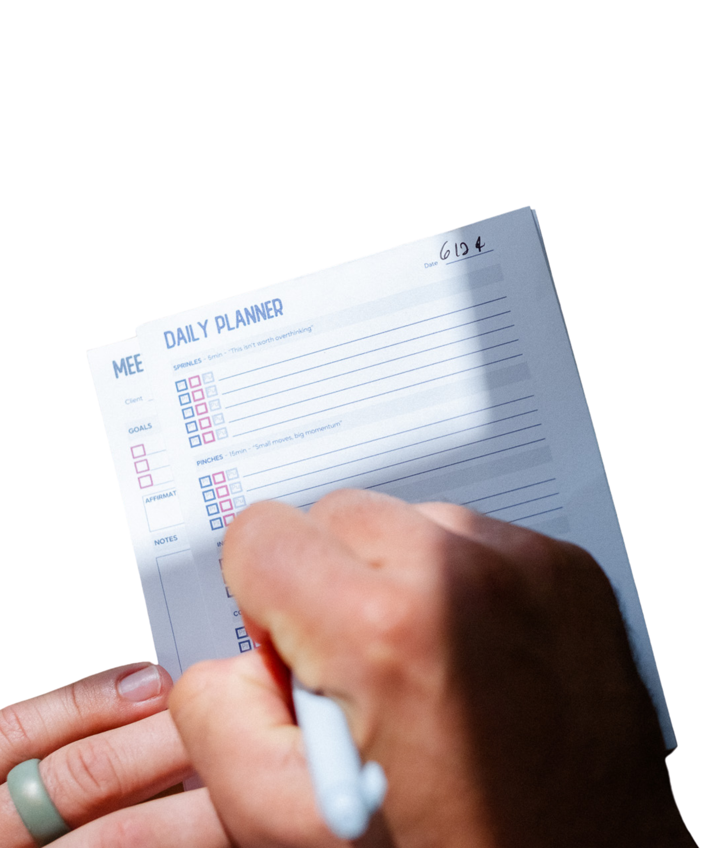 Close-up of a person's hand holding a white pen and writing on PowerSpeak Academy planner sheets.