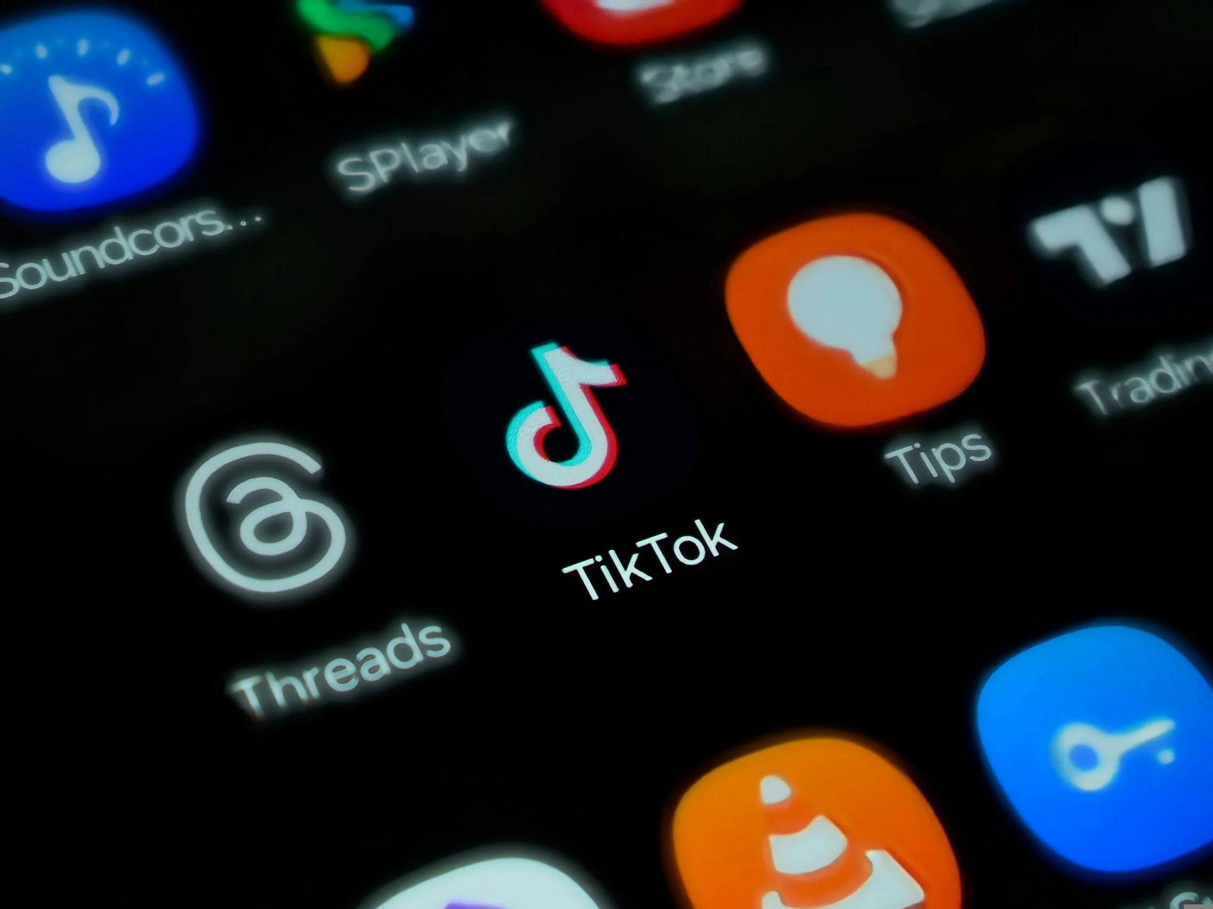Close-up of a smartphone screen displaying various app icons including TikTok, Tips, Threads, Soundcans, and Recorder, with the TikTok icon in focus.