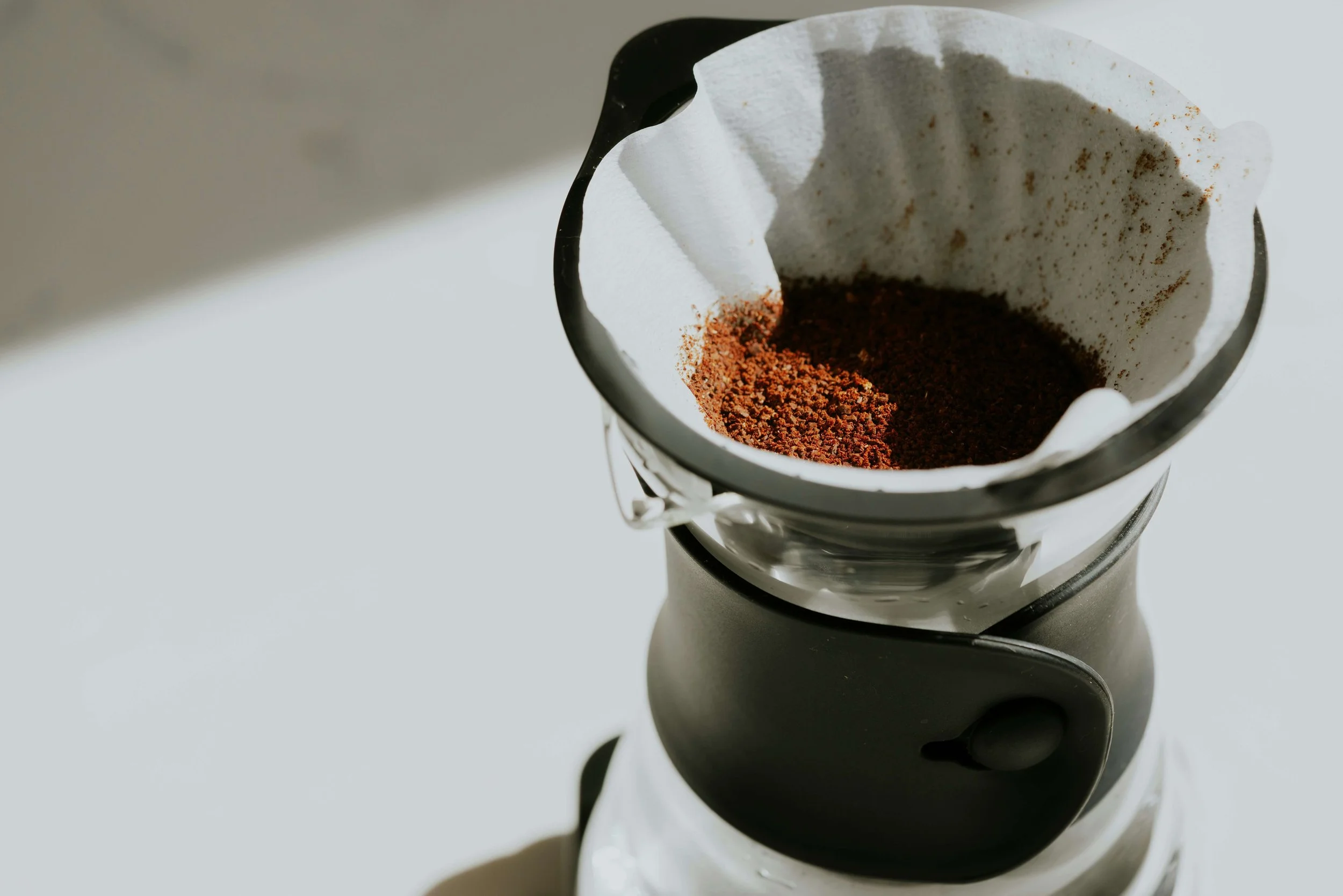 Coffee filter with ground coffee inside, placed in a coffee brewing machine.