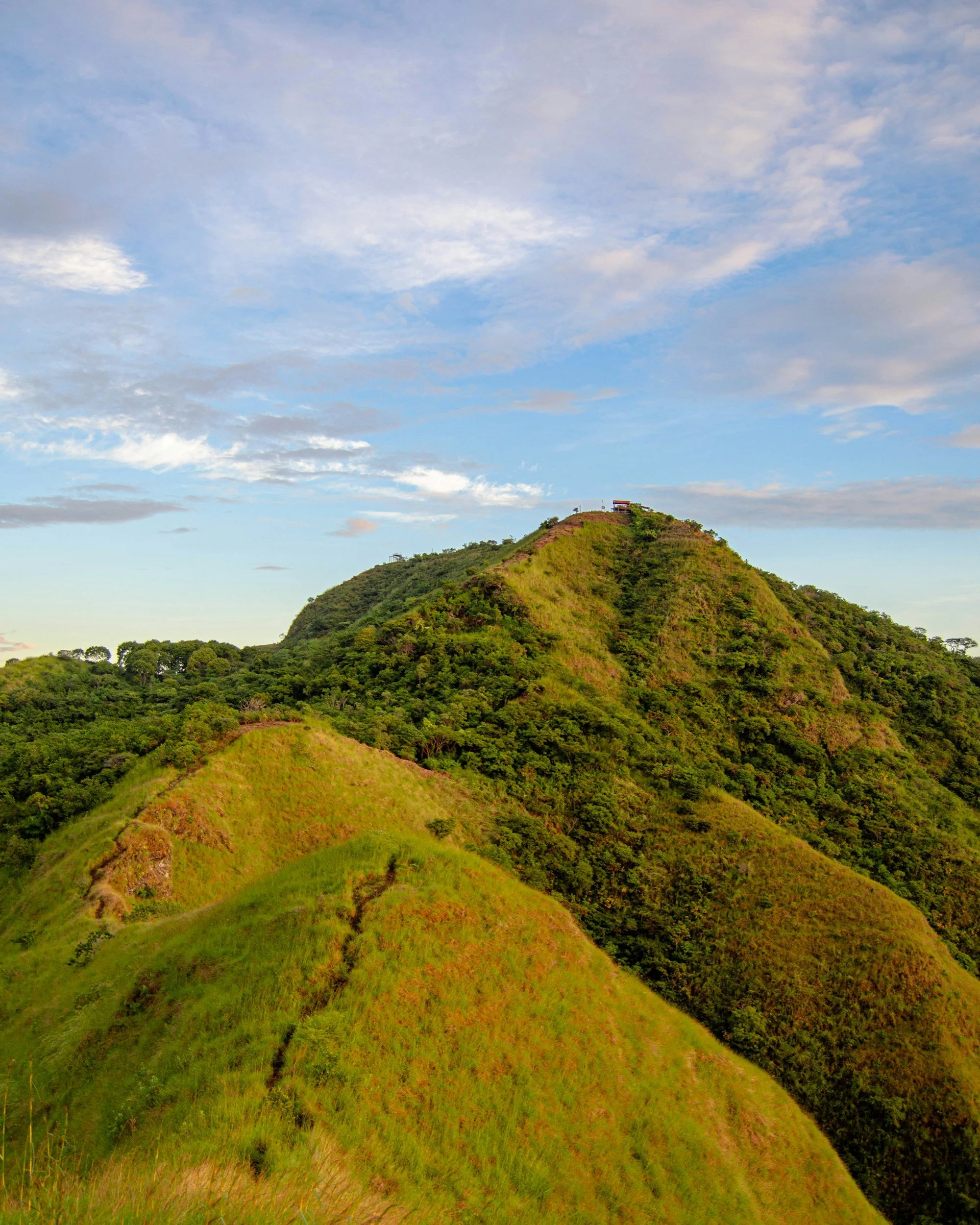 Green hills and mountain peaks under a partly cloudy sky.