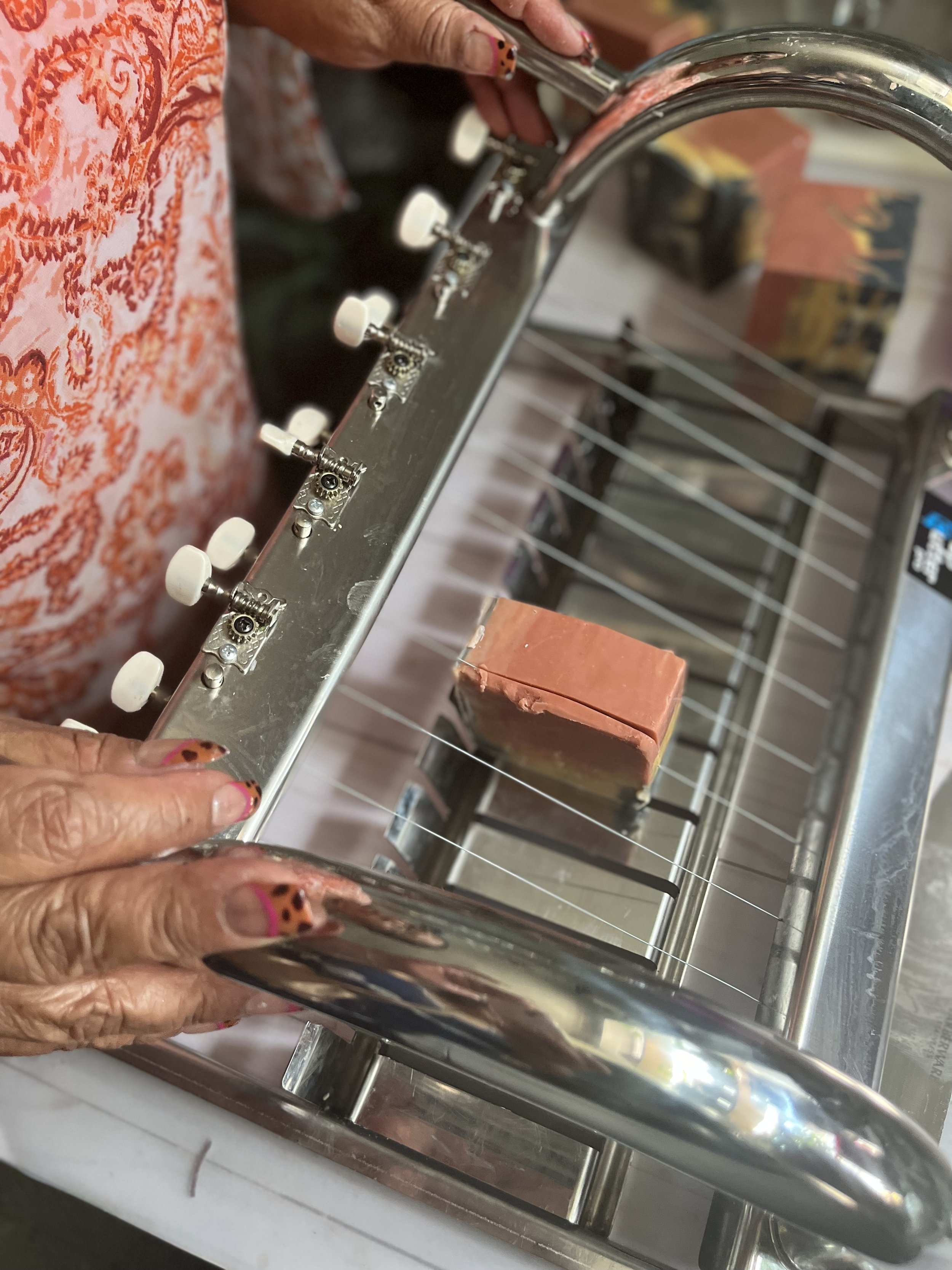 Person holding a metal soap dish with a bar of pink soap inside
