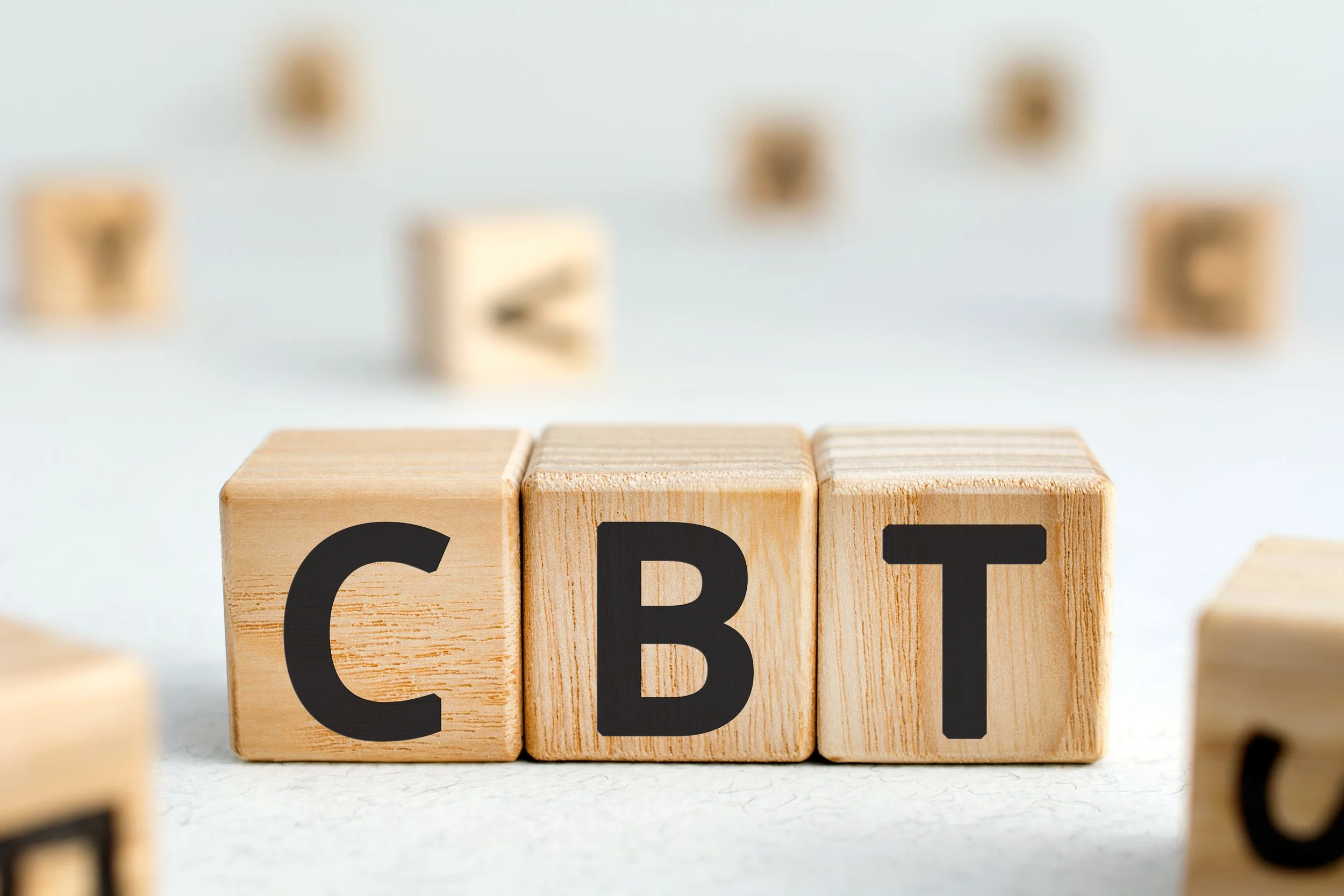 Wooden blocks spelling out 'CBT' with other blurred wooden blocks in the background.