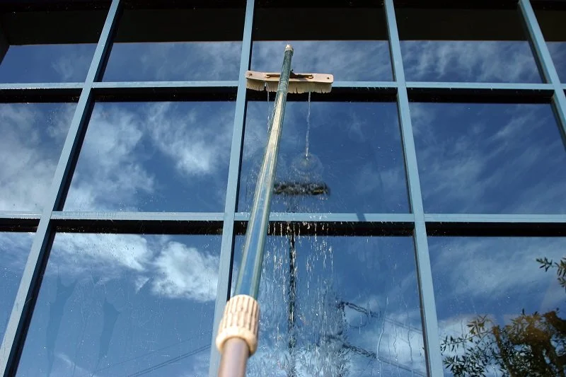 Cleaning the exterior glass window of a building using a squeegee.