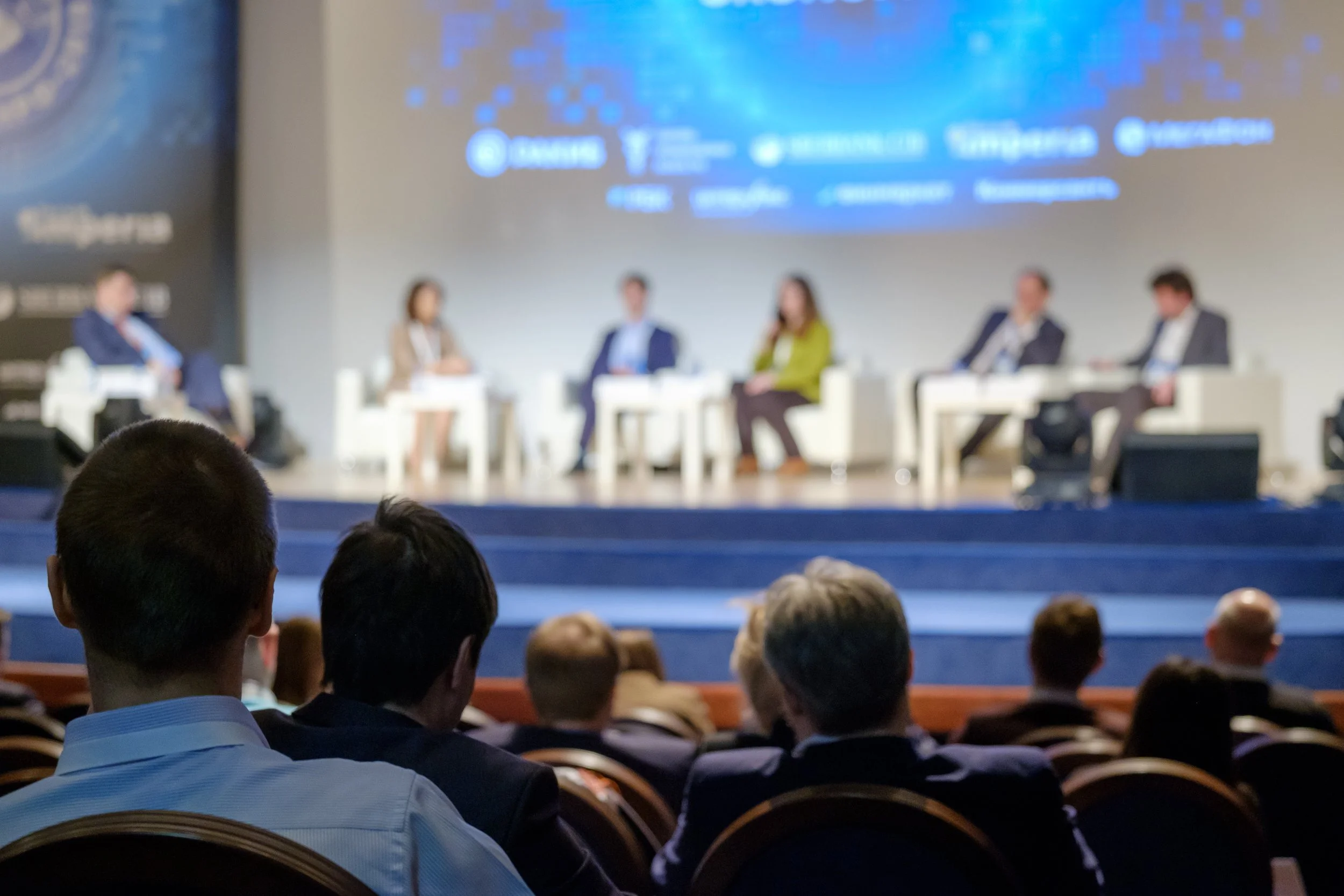 Panel discussion at a conference, showcasing strategic event programming and executive thought leadership—five speakers on stage with an engaged audience.