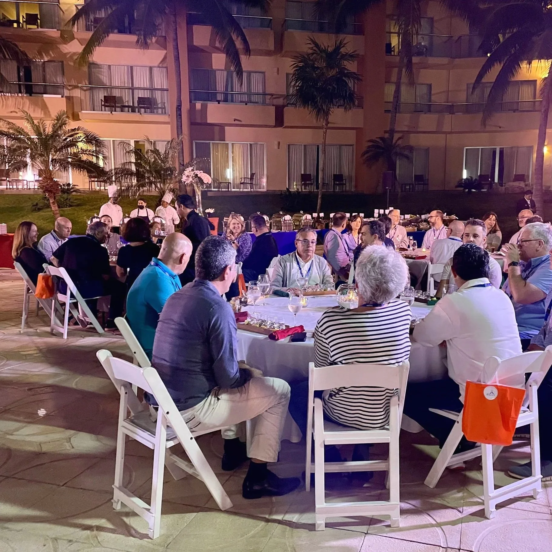 First night SKO dinner on the outside terrace, Cancun MX.  Multiple round tables with guests seated enjoying dinner. 