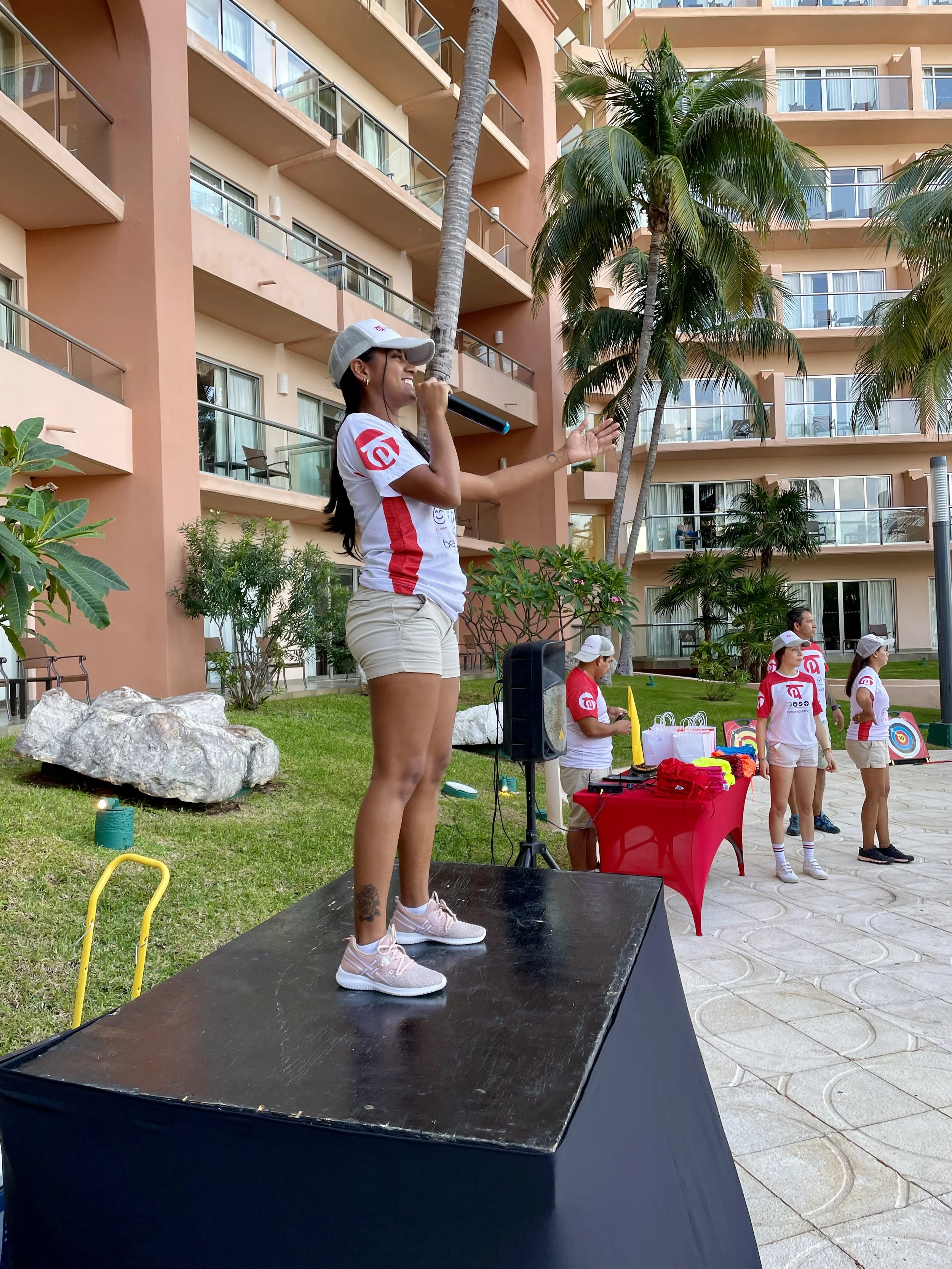 DMC partnership arranged for a Team Building Group to get the leaders excited to participate.  Young woman standing on table with microphone getting the group ready to play. 