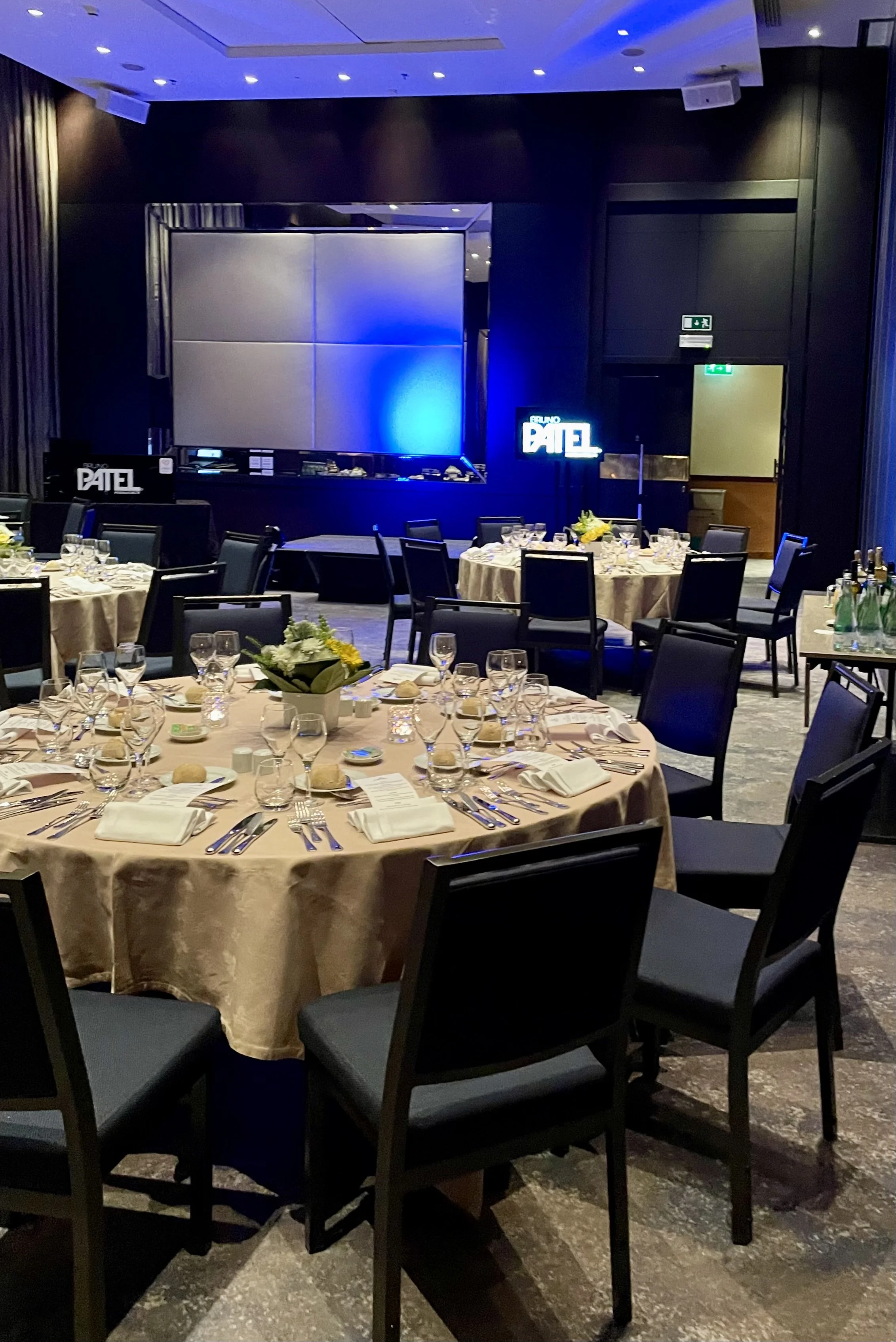 Tables set for dinner for attendees, with Karaoke stage in the background. 