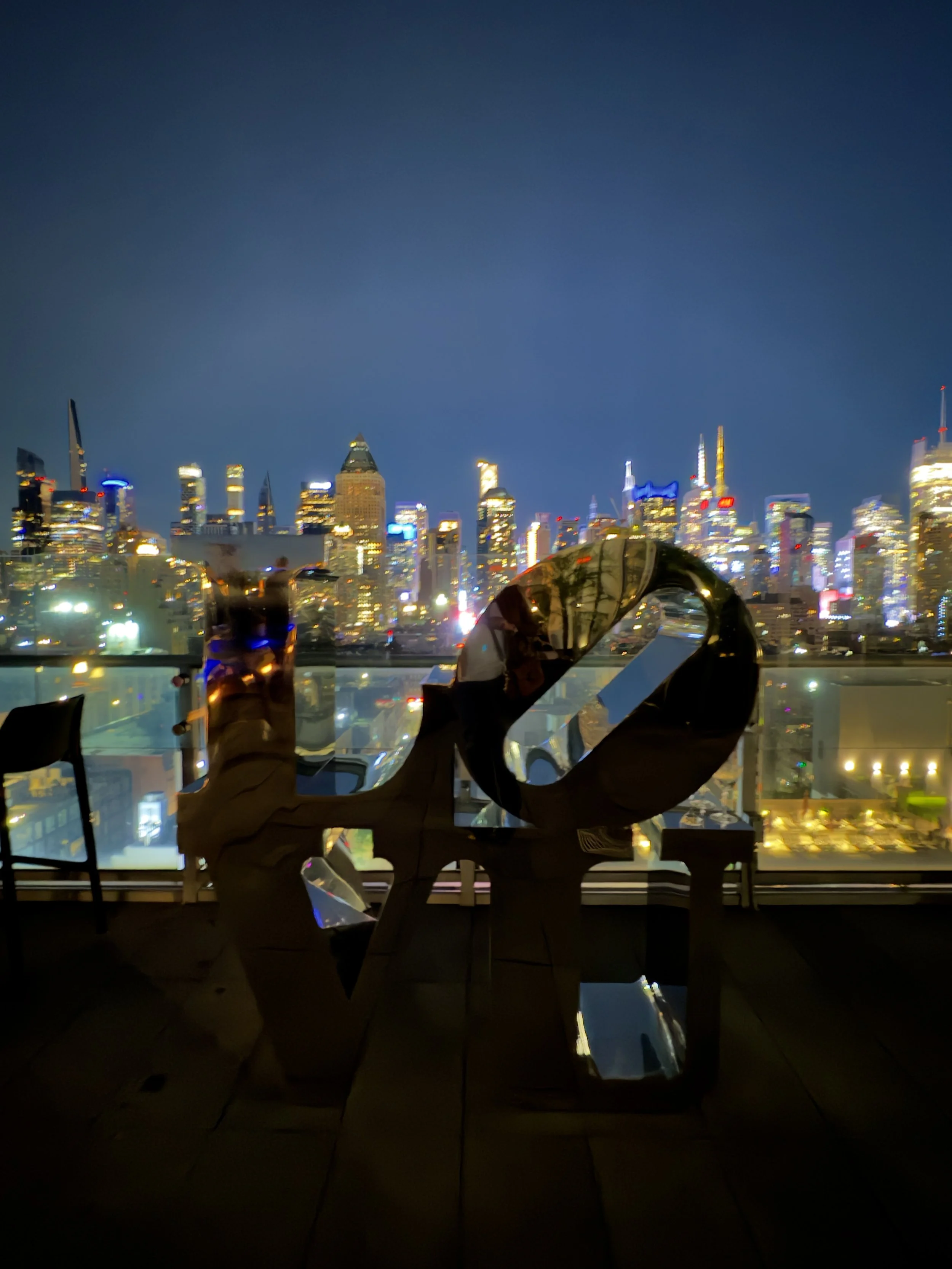 Rooftop bar view of the NYC skyline with a LOVE sculpture in the foreground