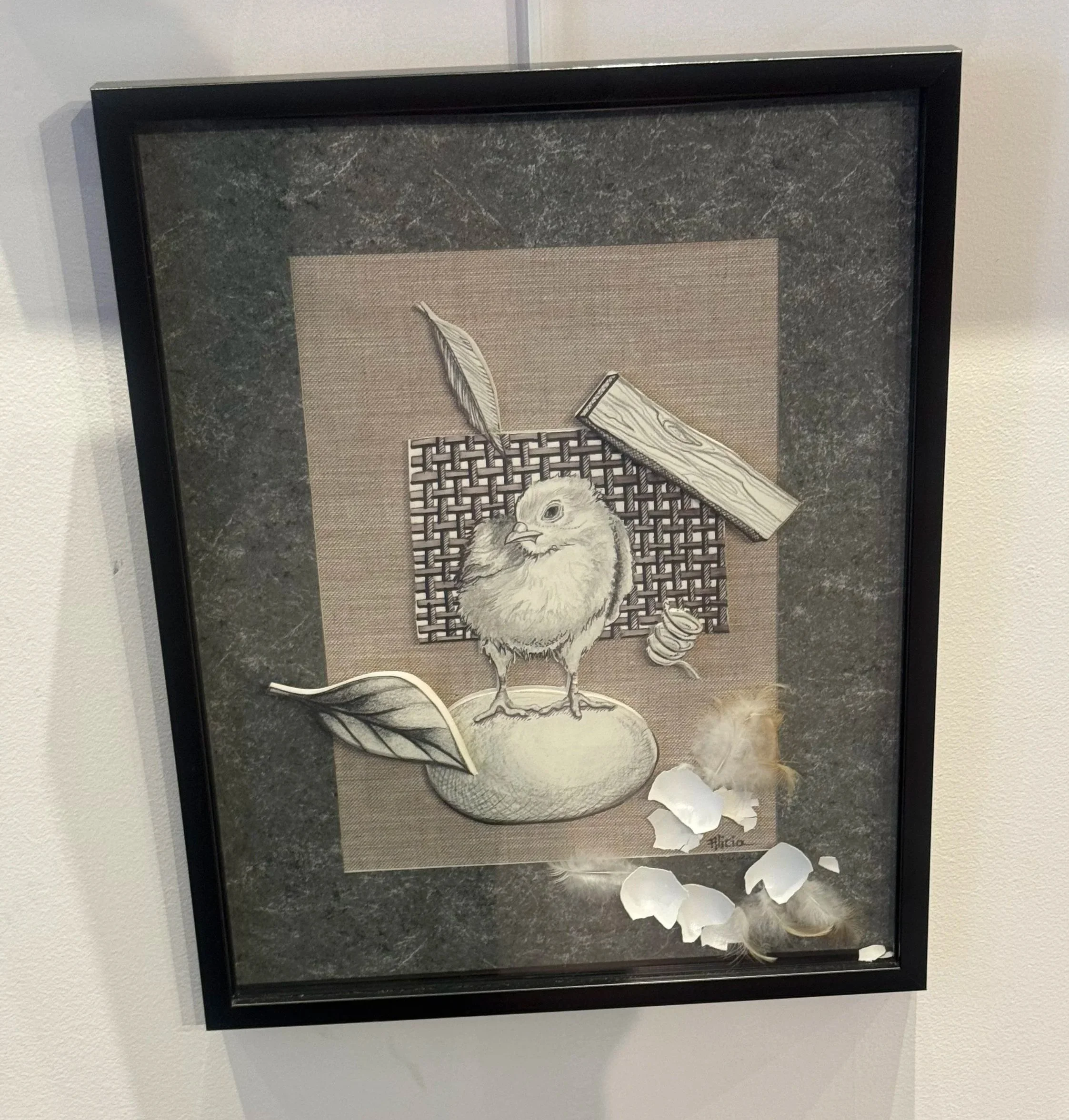 Mixed-media artwork featuring a chick standing on a rounded surface with feathers, a leaf, a spool of thread, and a wooden block, with a woven background and layered textures.