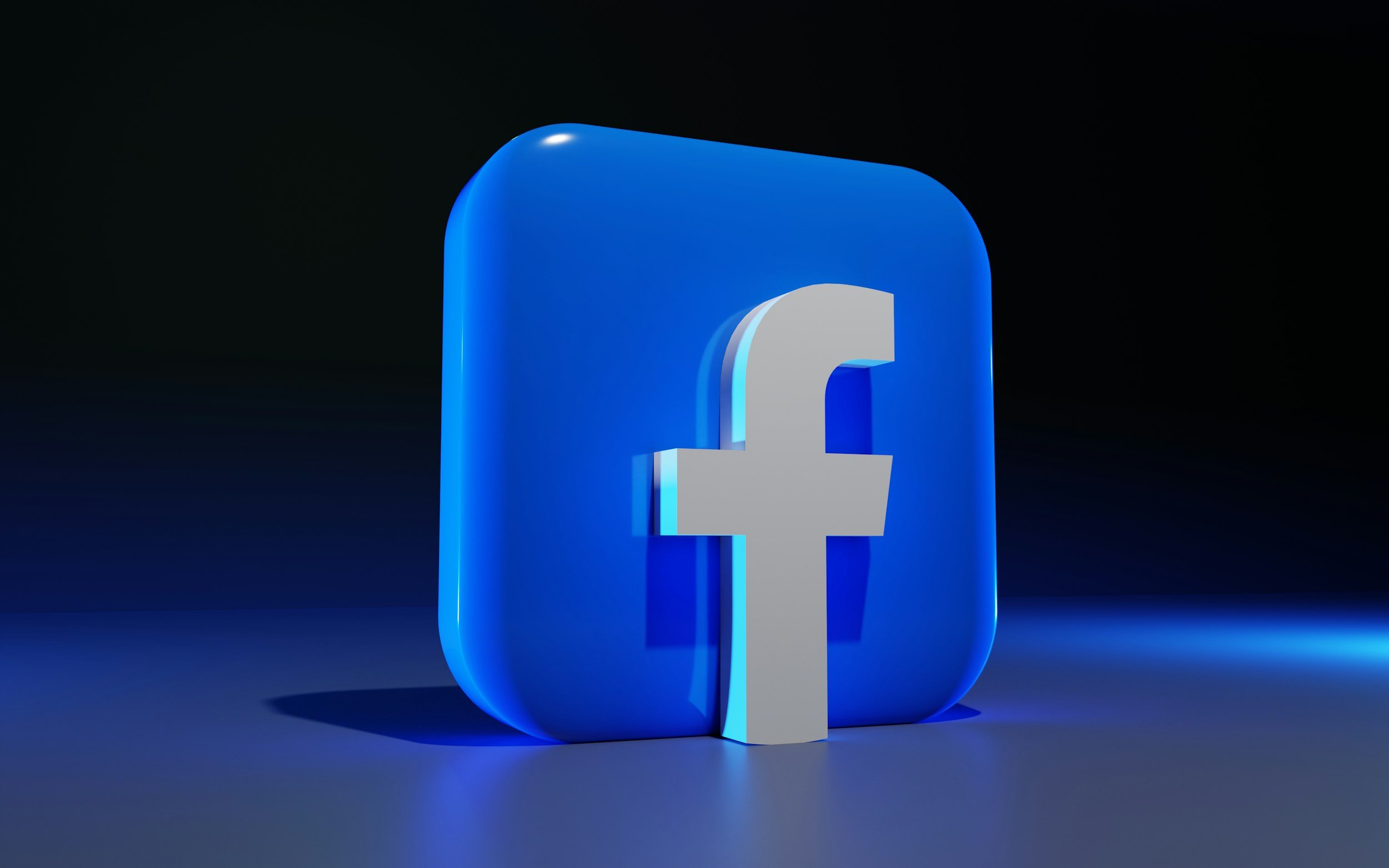 3D rendering of a Facebook logo, with the white letter 'f' on a blue square background, illuminated in a dark setting.