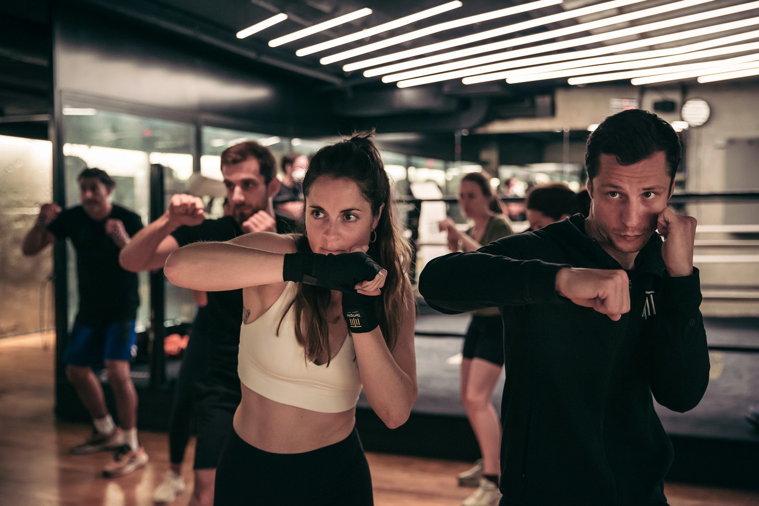 People participating in a boxing fitness class, practicing punches in a gym.