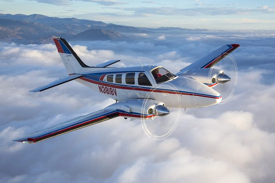 White and black twin-engine propeller airplane parked on tarmac at airport.