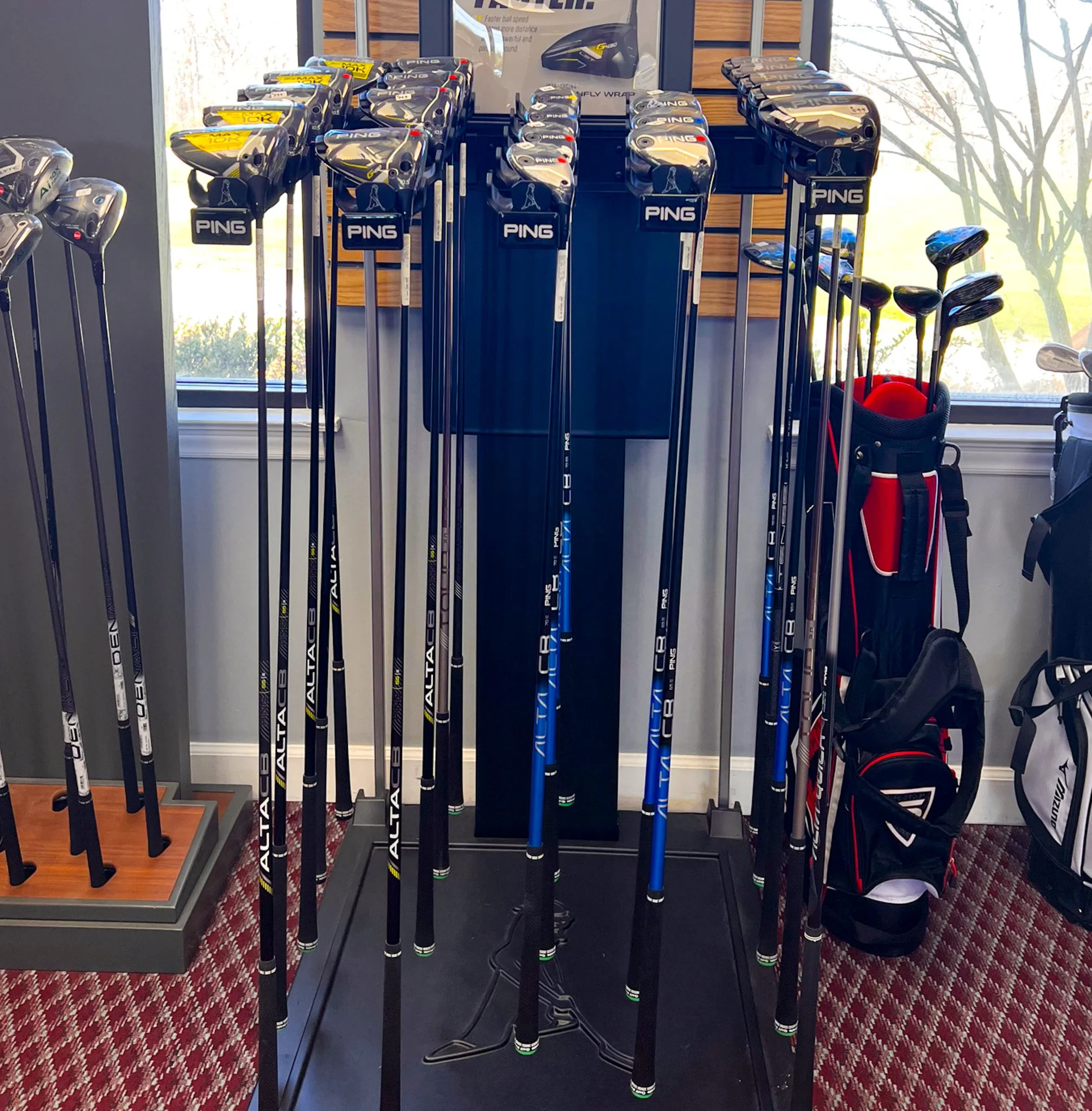Display rack with various golf clubs, including drivers and irons, at a golf store.