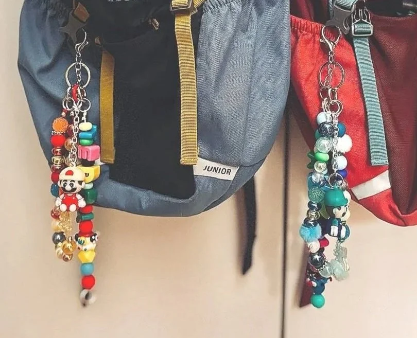 Colorful beaded and character keychains hanging from backpacks.