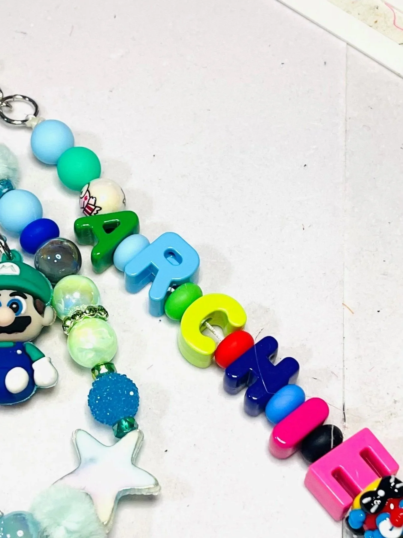 Colorful beaded necklace with characters from Super Mario and other decorative beads on a white background.