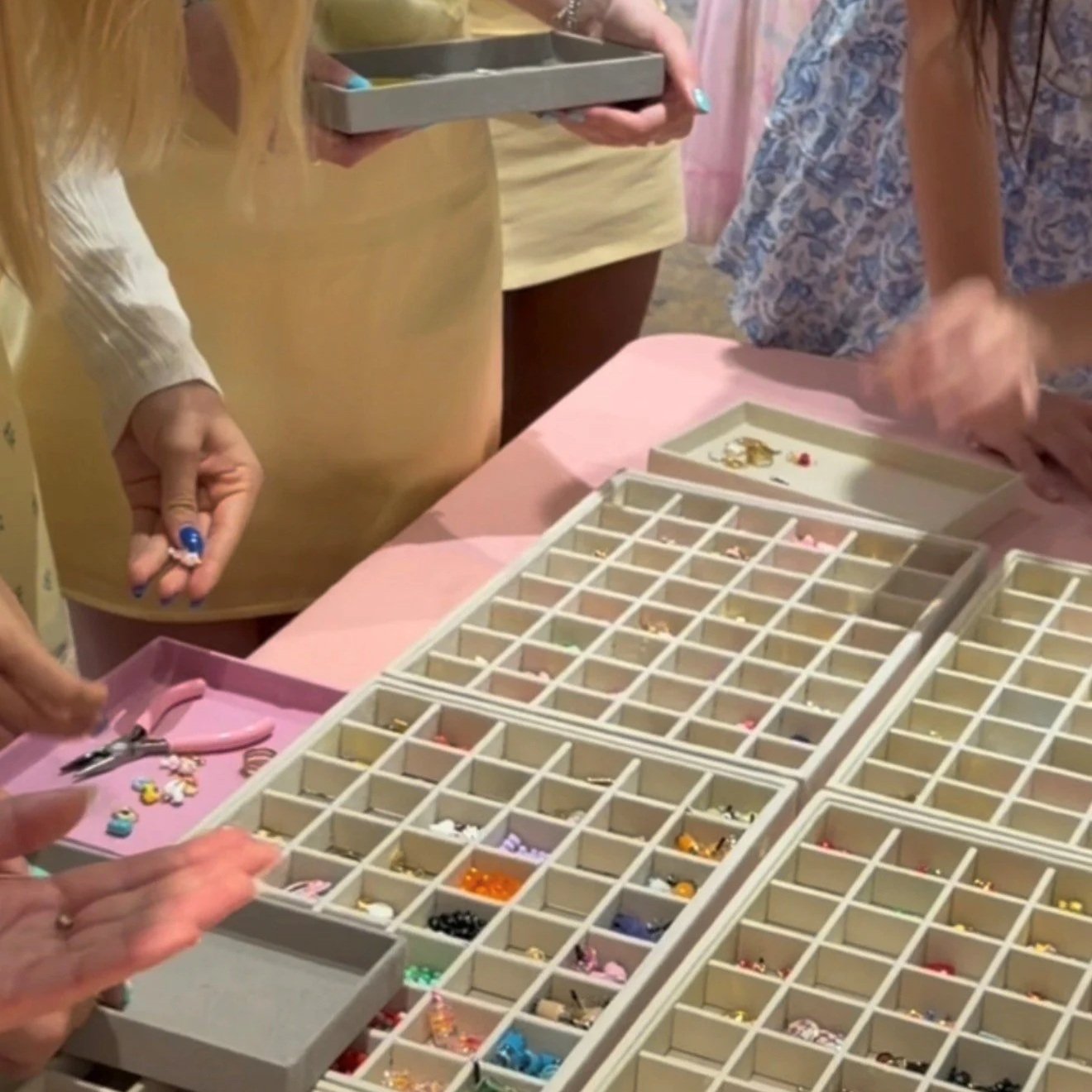 A jewelry organizer filled with various bracelets, rings, and earrings, with several people browsing and selecting jewelry pieces.