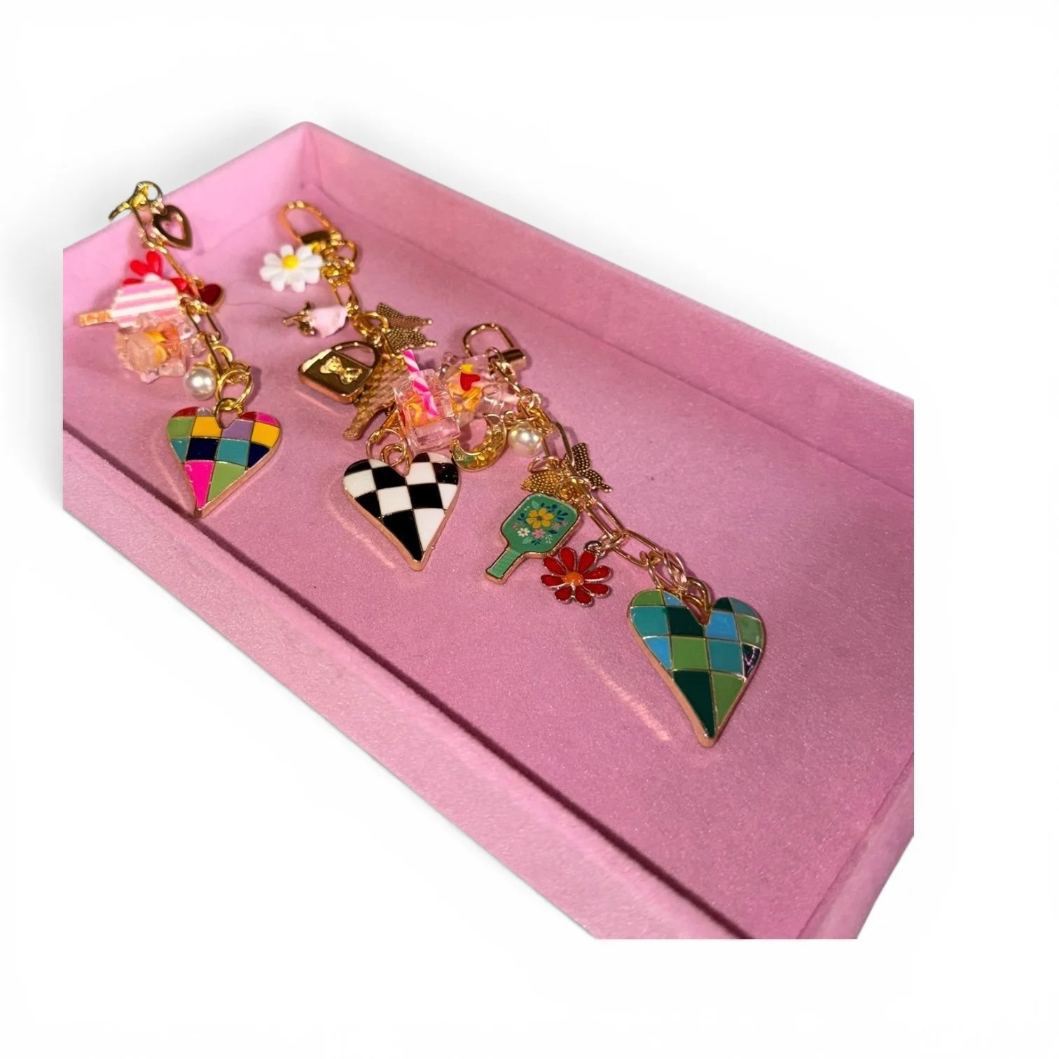 Pink jewelry box containing colorful enamel charm bracelets with hearts, flowers, and other playful charms.