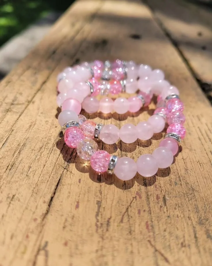 Pink beaded bracelet with rhinestone accents on a wooden surface.