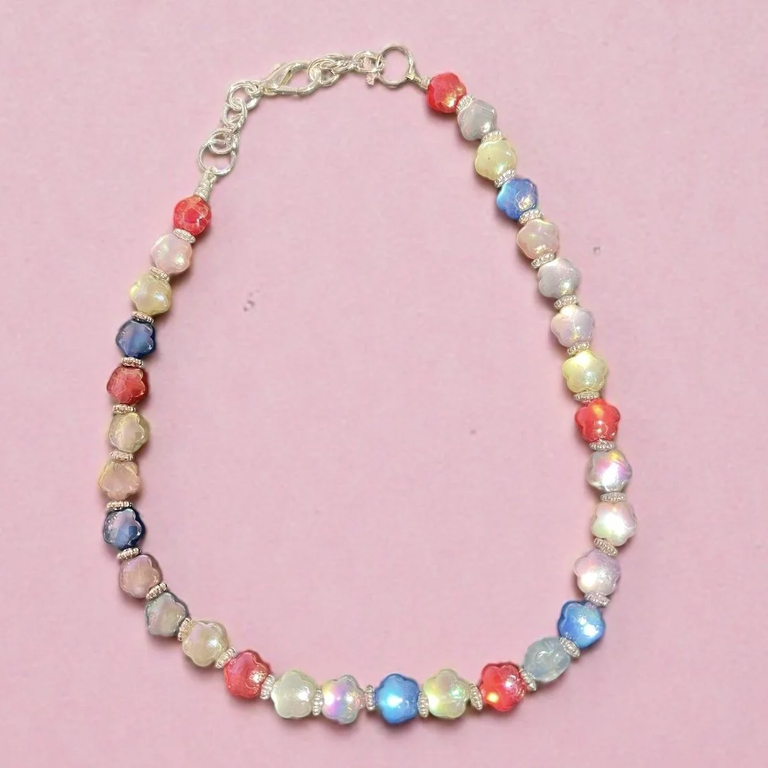 Colorful beaded necklace with pastel and bright beads on a pink background.