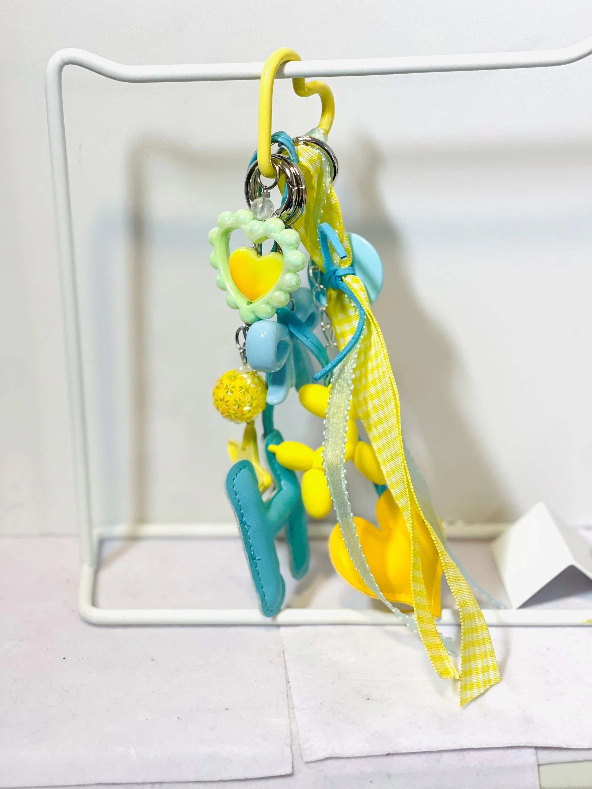 Collection of yellow and blue baby teething toys and rattles hanging from a white metal stand.